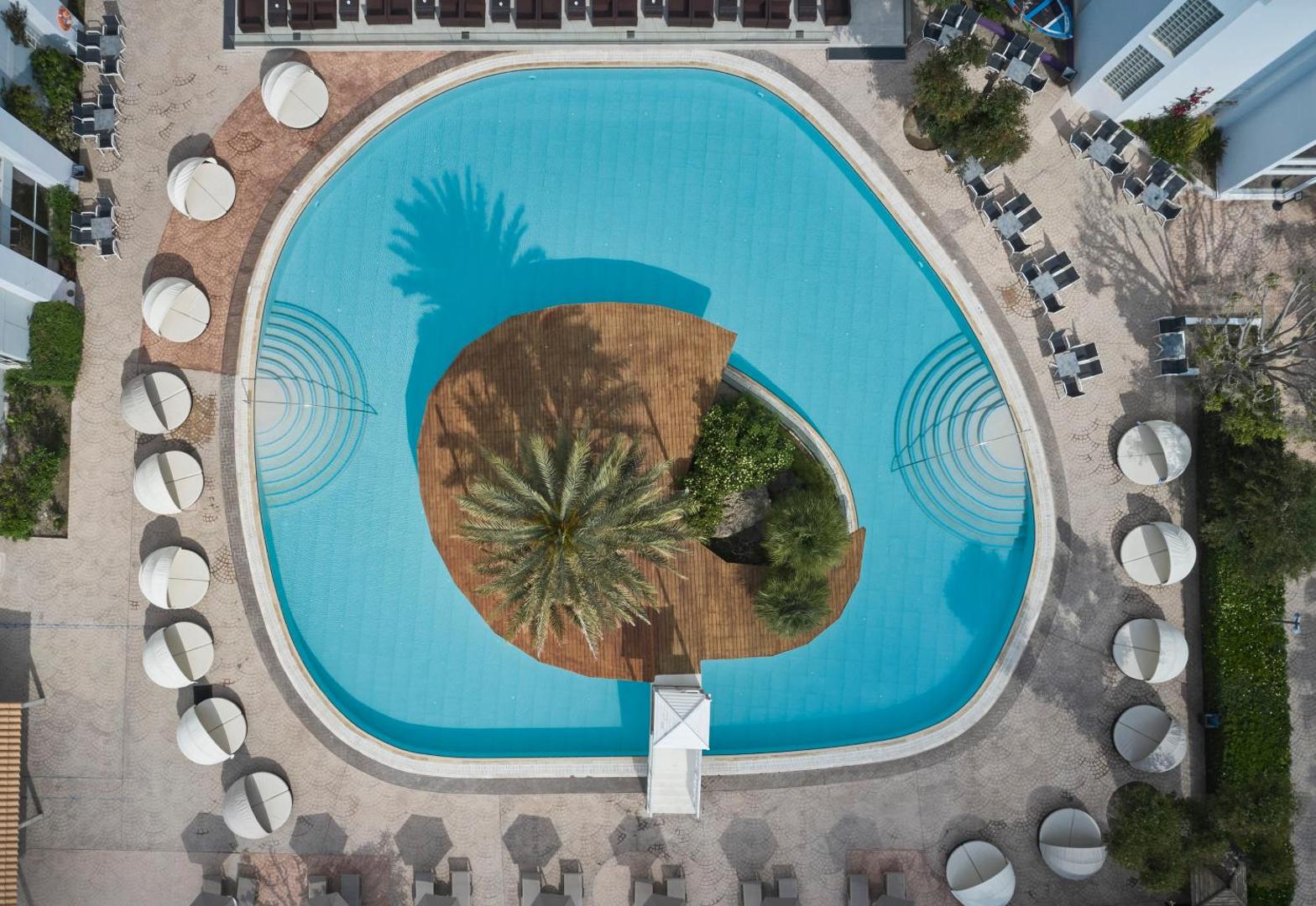 Esperides Beach Resort apaļš baseins ar koka terases salu un palmu centrā, skats no augšas