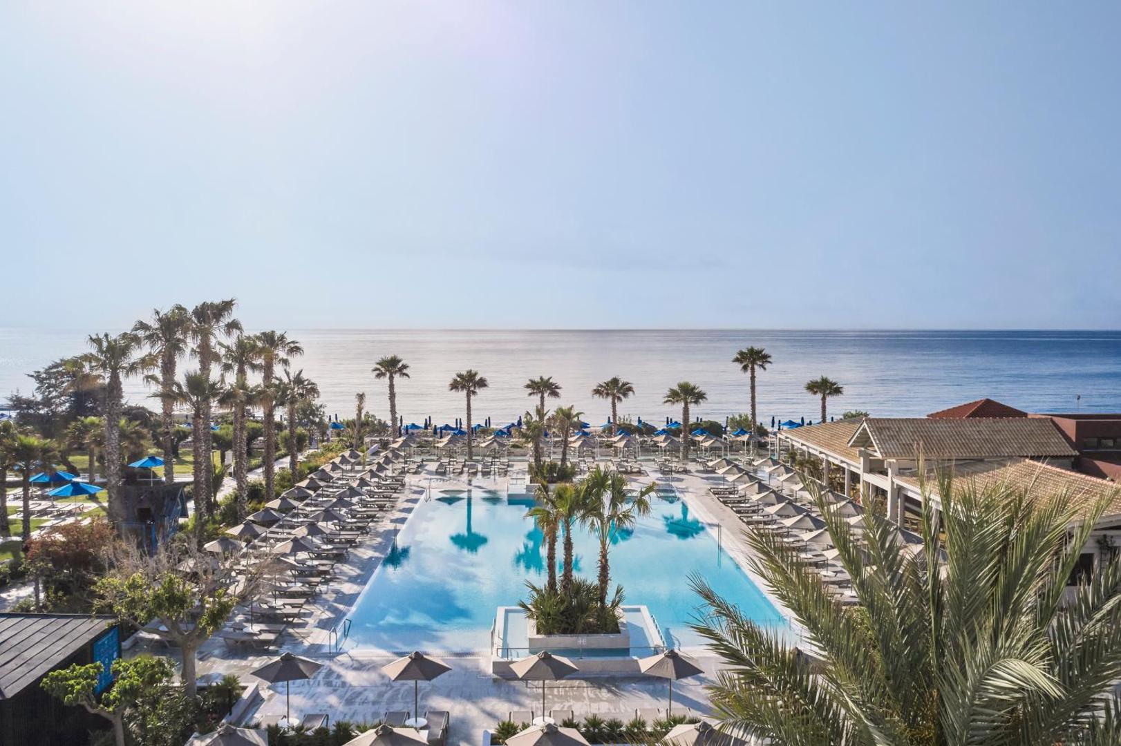 Esperides Beach Resort galvenais āra baseins Rodas salā ar skatu uz jūru, saulessargiem un palmām piekrastē
