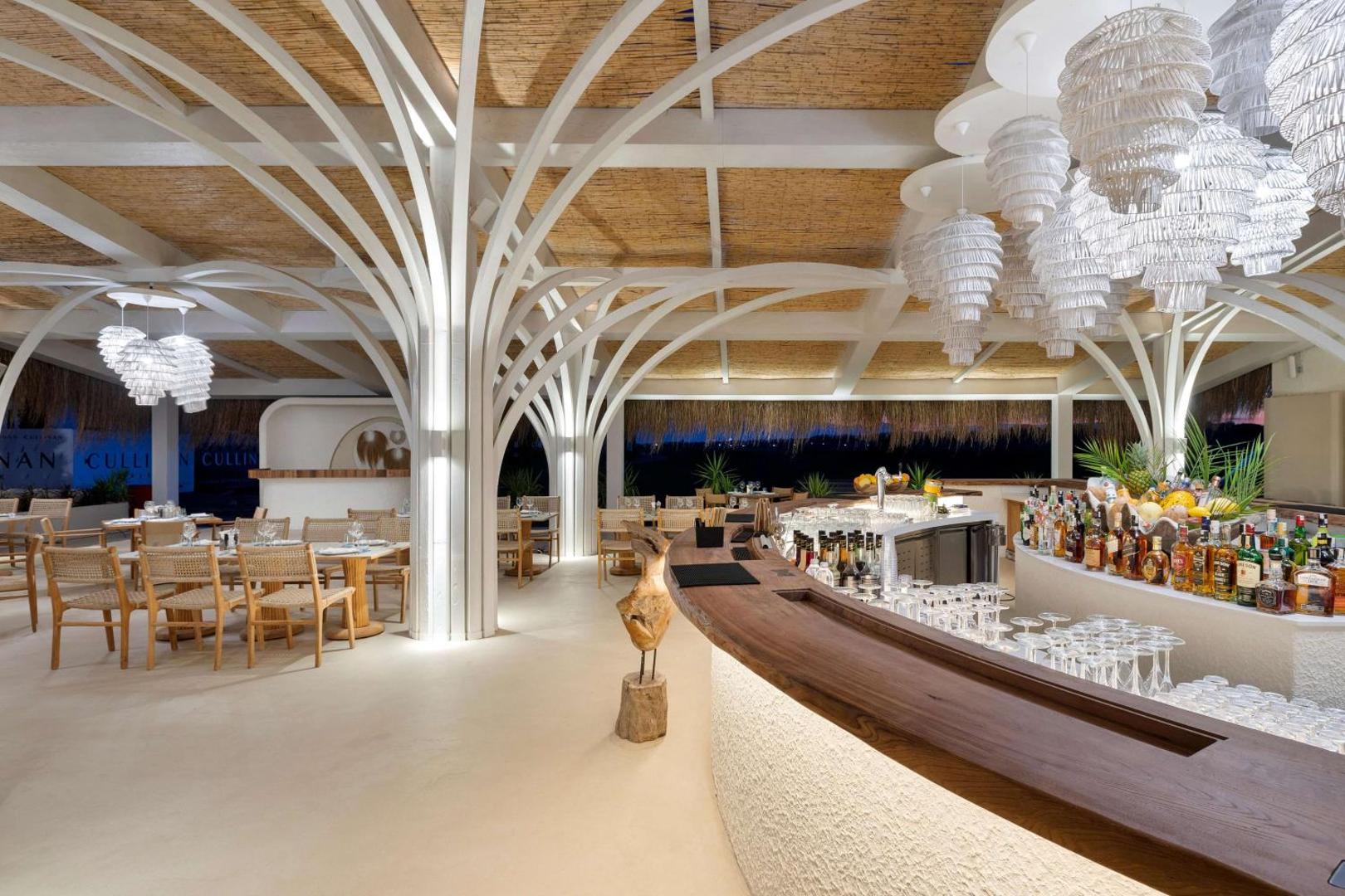 Cullinan Golf & Resort pludmales bārs un restorāns ar unikālu koka arhitektūru, dizaina lampām un skatu uz jūru vakarā.