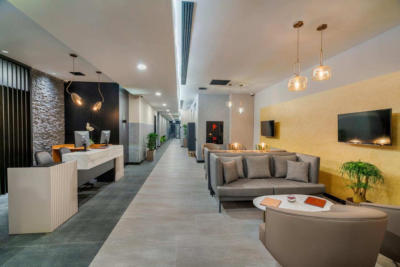 Viesnīcas Corendon Playa Kemer modernā recepcijas zona un vestibils ar ērtiem dīvāniem, atpūtas krēsliem un gaišu interjeru Kemeras kūrortā