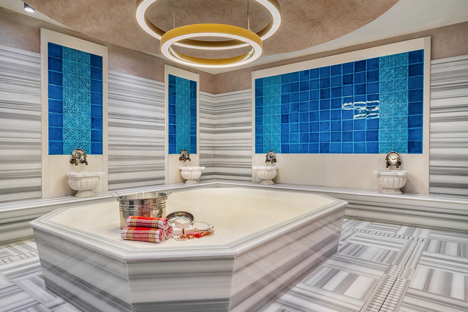 Corendon Playa Kemer spa centra turku pirts jeb hamams ar marmora apdari, ziliem flīžu akcentiem un tradicionāliem mazgāšanās piederumiem.