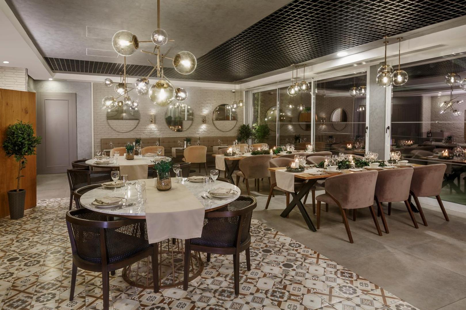Corendon Playa Kemer elegants iekštelpu restorāns ar modernām lustrām, marmora galdiem un mīkstiem krēsliem, radot mājīgu un izsmalcinātu atmosfēru.