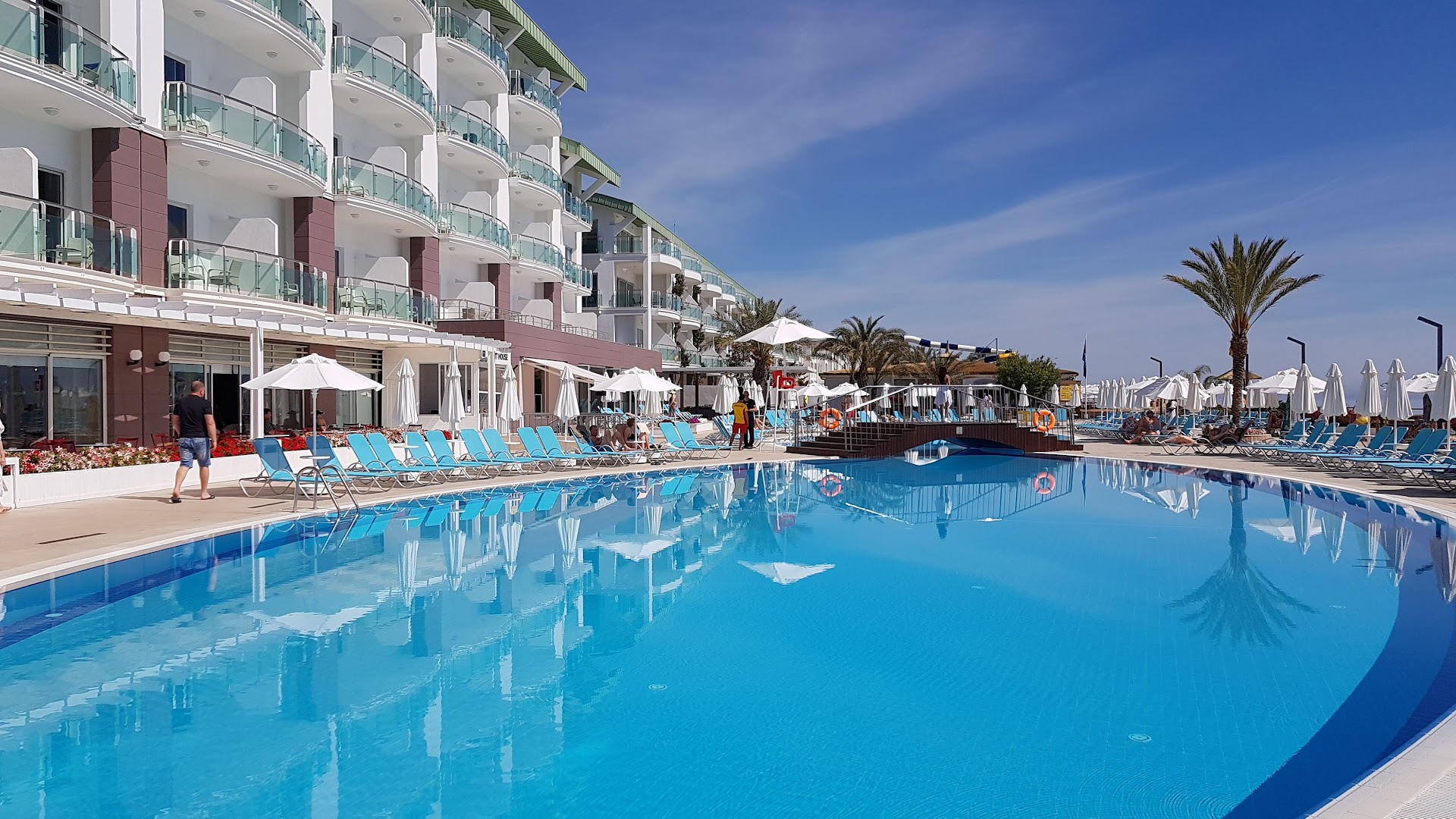 Corendon Playa Kemer viesnīcas fasāde ar balkoniem un galveno baseinu saulainā dienā Kemeras reģionā, Turcijā