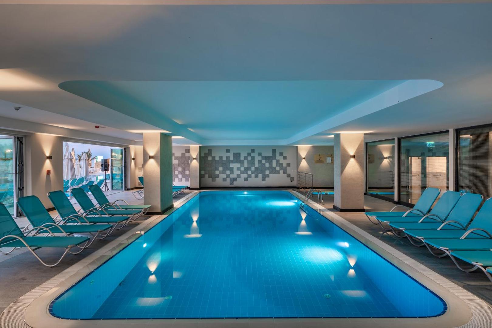 Corendon Playa Kemer iekštelpu baseins ar ziliem atpūtas krēsliem un modernu apgaismojumu spa zonā Kemeras reģionā, Turcijā