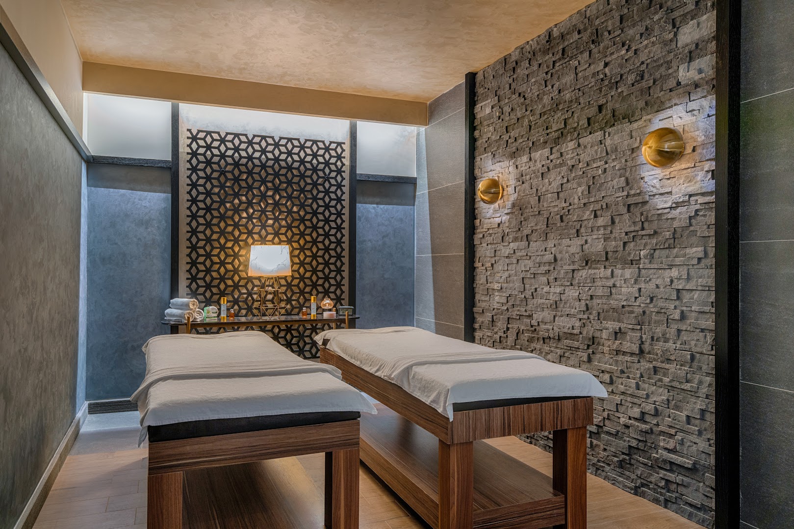 Corendon Playa Kemer spa centra masāžas telpa ar divām kušetēm, akmens sienas apdari un siltu, relaksējošu apgaismojumu Antaljas reģionā