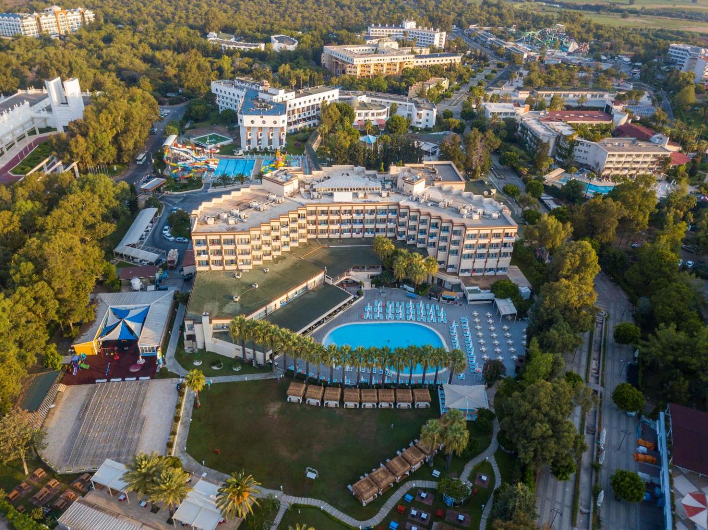 Asteria Collection Side viesnīcas ēka un galvenais baseins no putna lidojuma — apkārtnē zaļojošs dārzs un atpūtas zona ar saulessargiem