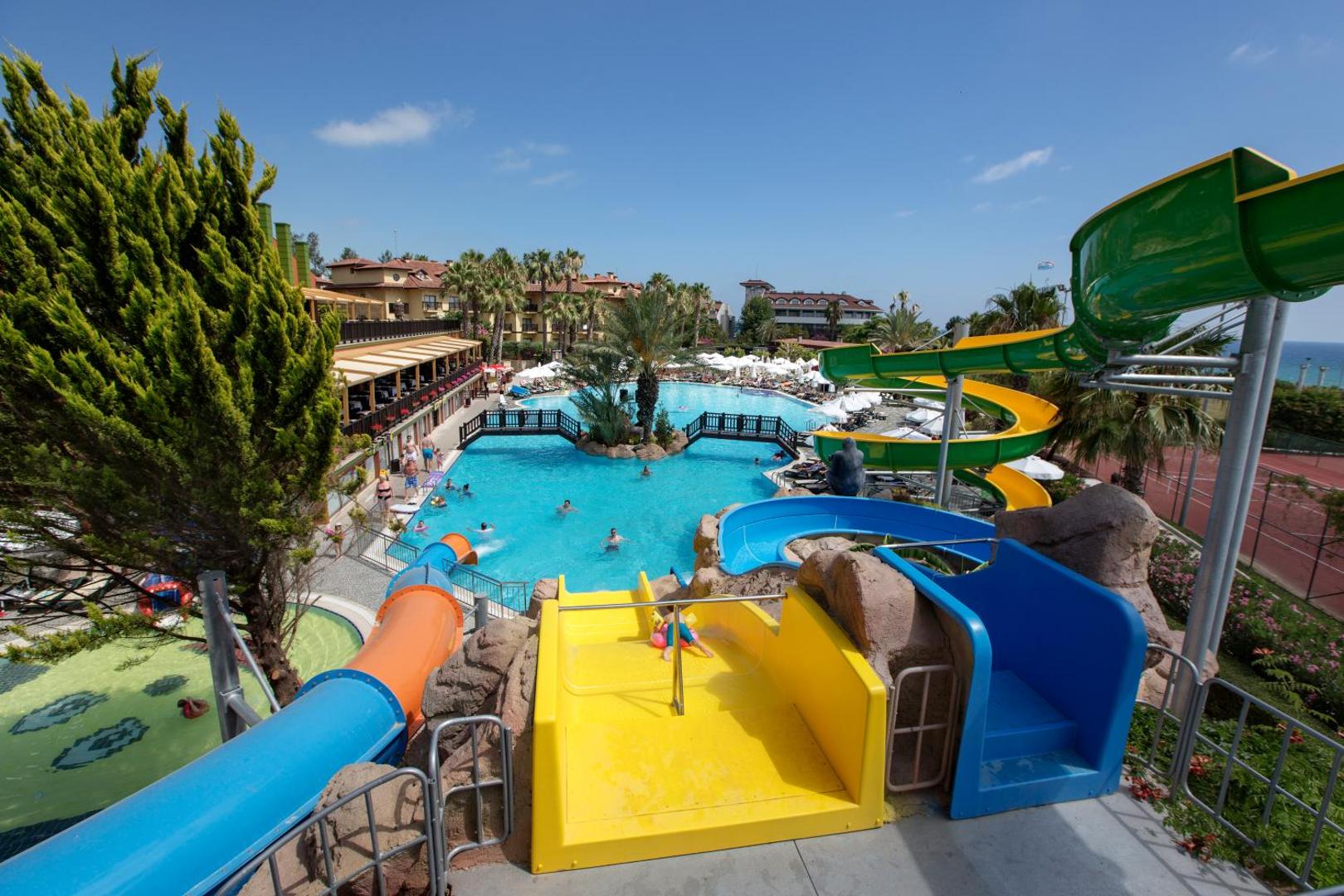 Alba Resort Hotel ūdens atrakciju zona ar ziliem un dzelteniem slidkalniņiem, skats no starta platformas uz baseinu.