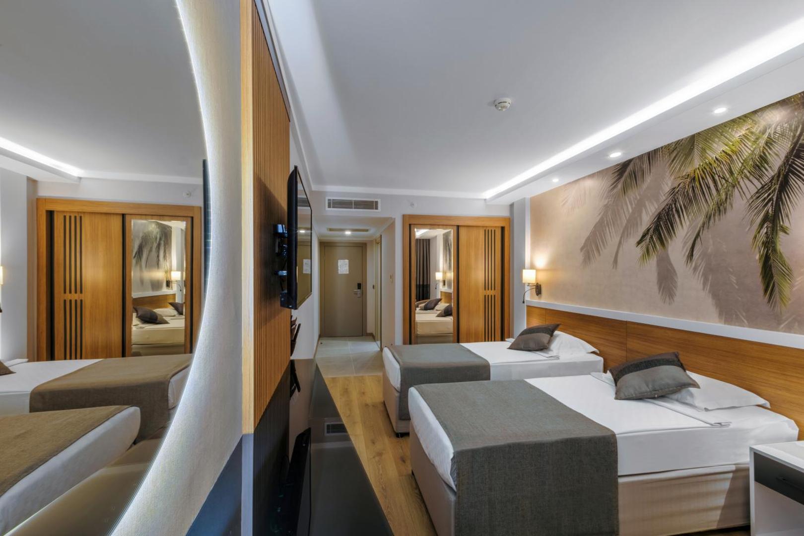 Alba Resort Hotel moderns divvietīgs numurs ar divām gultām, koka paneļu sienu, lielu spoguli un tropisku sienas dekoru Sides reģionā