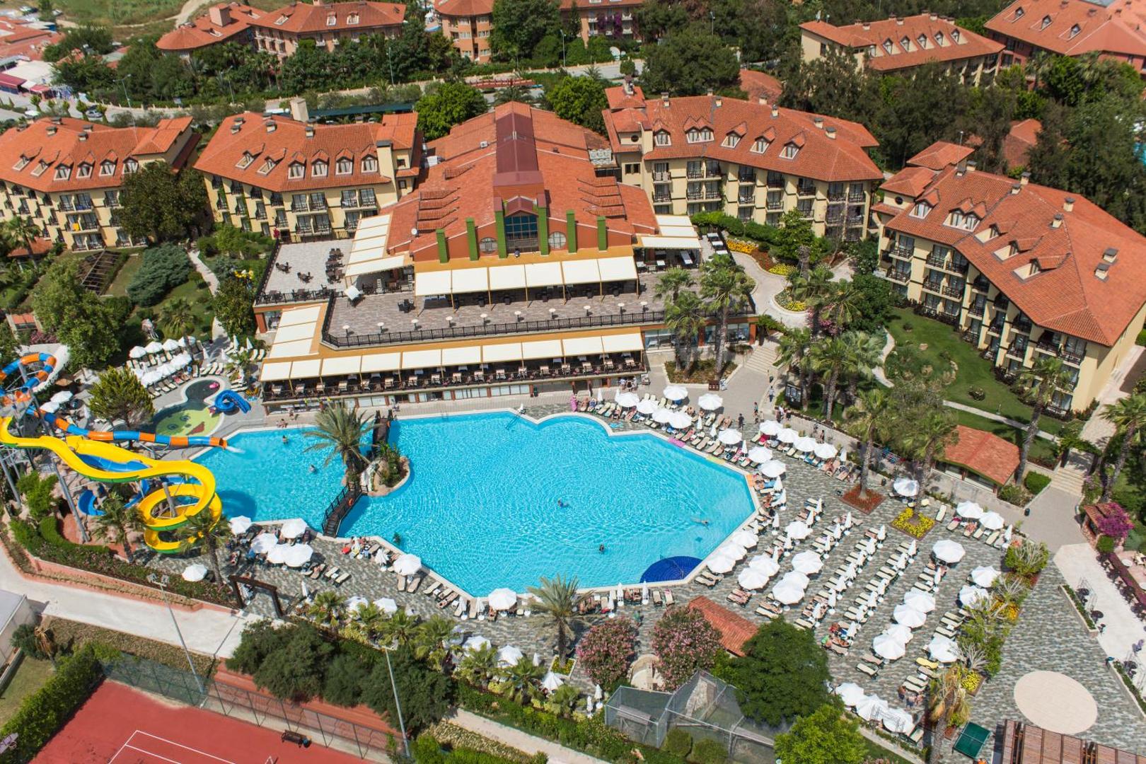 Alba Resort Hotel galvenais baseins un sauļošanās zona ar saulessargiem, skatoties no augšas uz centrālo ēku.