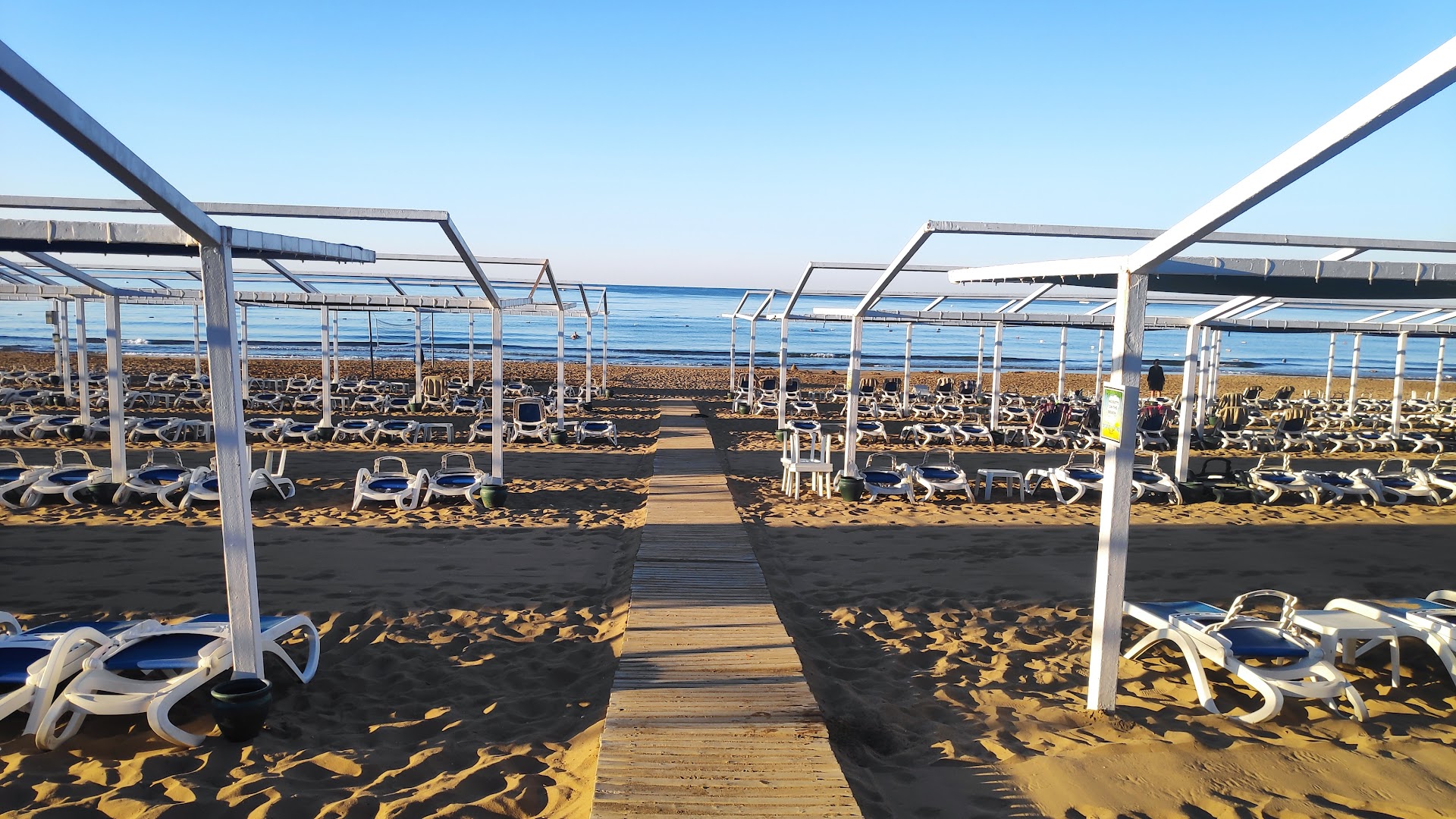 Alba Resort Hotel privātā smilšu pludmale Sidē ar koka laipu, sauļošanās krēsliem un nojumēm Vidusjūras krastā saulainā dienā