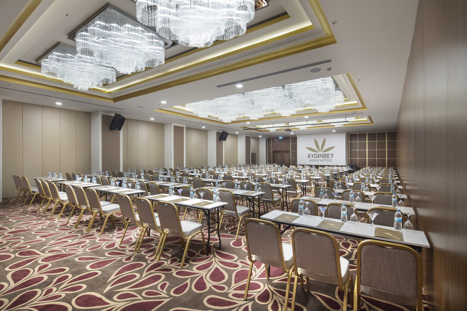 Aydinbey Queen's Palace & SPA plaša konferenču zāle ar greznām lustrām un sakārtotām sēdvietām pasākumiem Belekā