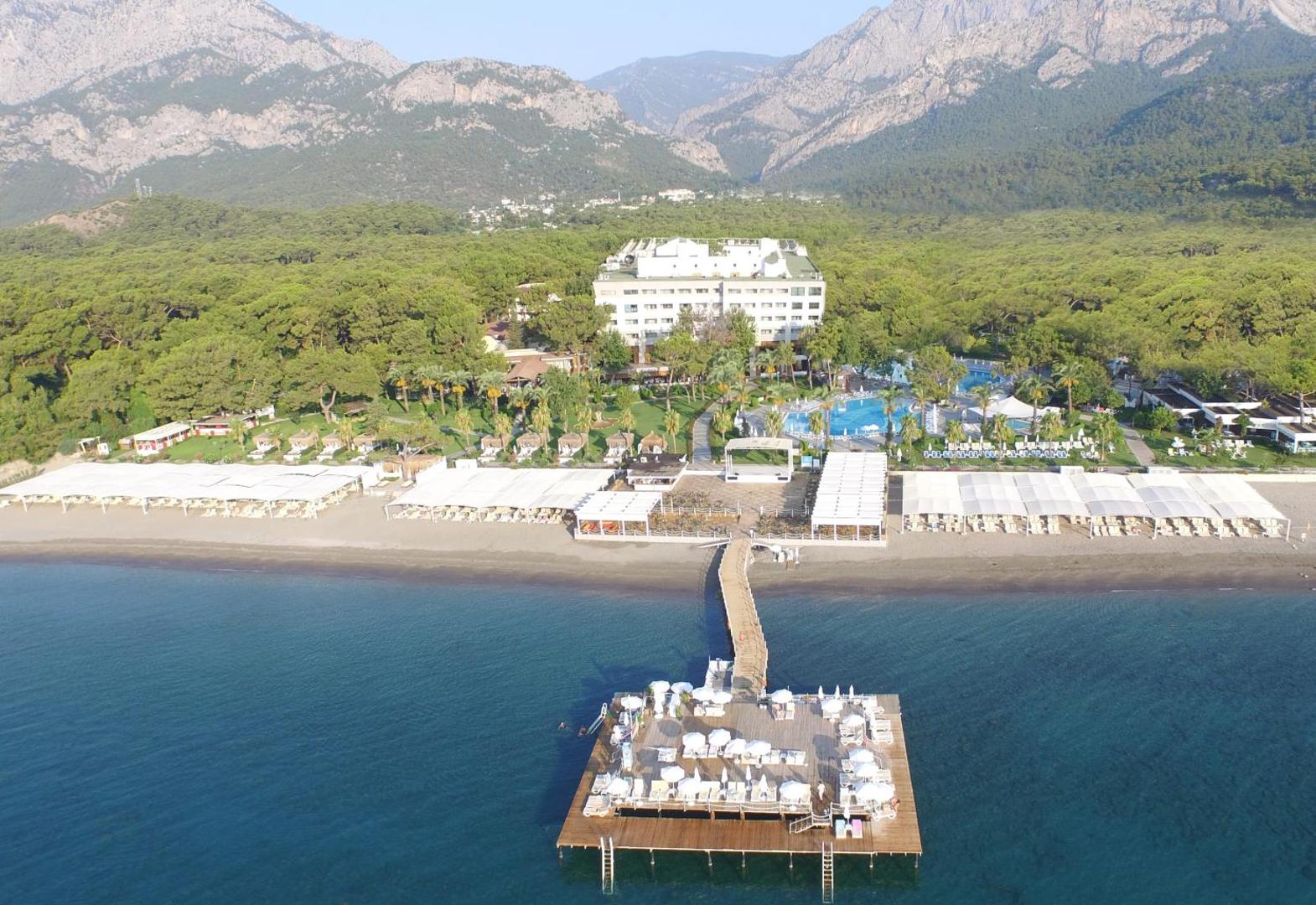 Mirada Del Mar Hotel skats no putna lidojuma Kemeras reģionā — viesnīcas ēka, baseinu zona un koka piestātne Vidusjūras piekrastē
