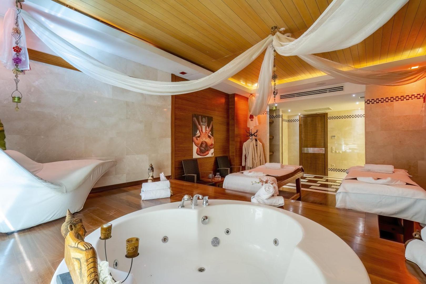 Mirada Del Mar Hotel spa centrs Kemeras reģionā — masāžas telpa ar divām gultām, džakuzi vannu un relaksējošu interjeru ar baltiem audumiem