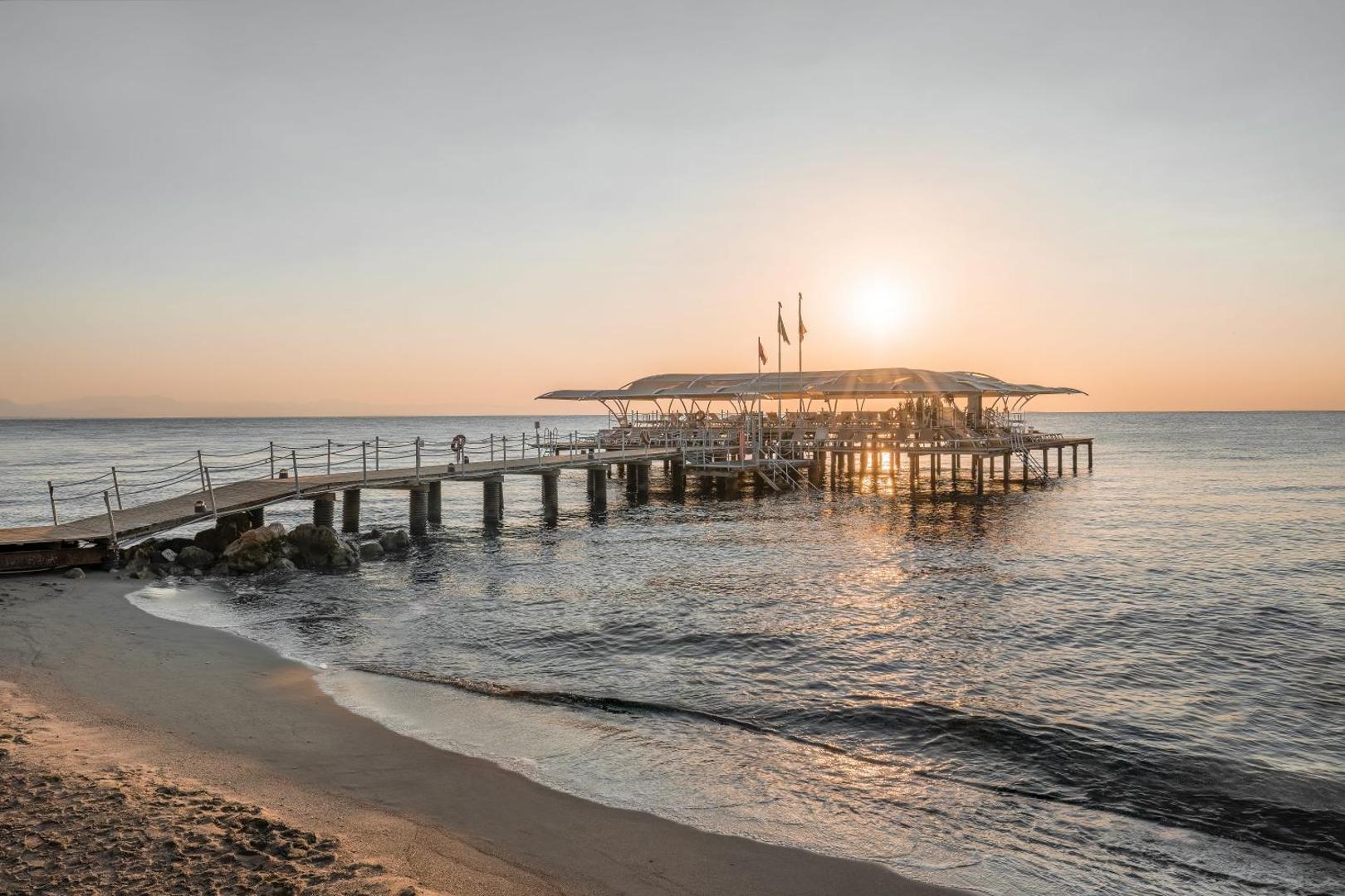 Mirada Del Mar Hotel koka piestātne un smilšu pludmale saulrieta laikā — skats uz Vidusjūras piekrasti Kemeras reģionā