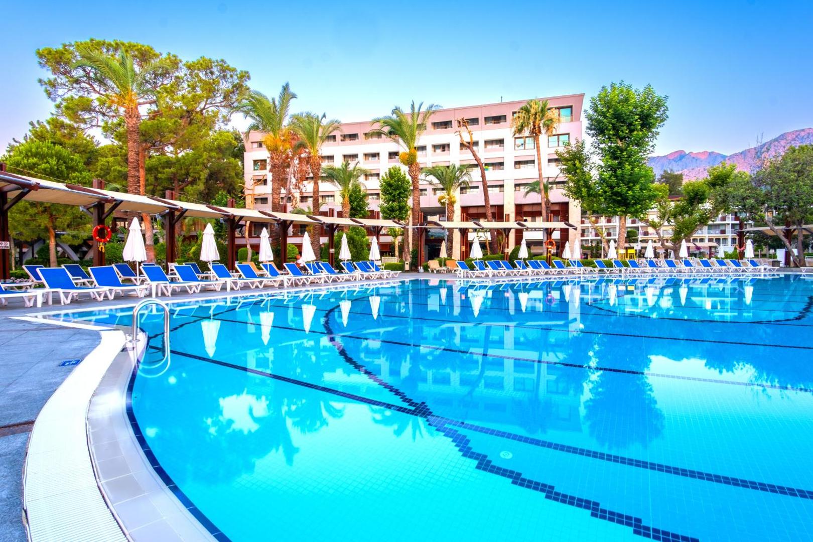 Mirada Del Mar Hotel galvenā ēka un lielais āra baseins Kemeras reģionā — sauļošanās krēsli, palmas un kalnu fons