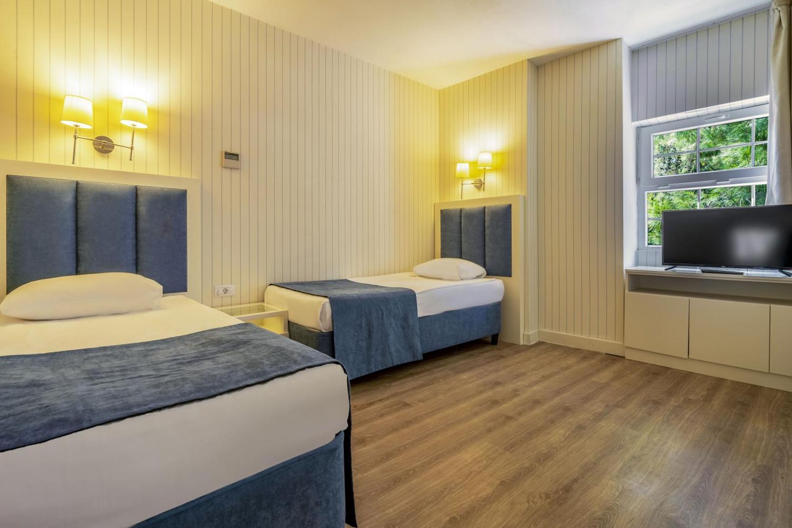 Mirada Del Mar Hotel numurs ar divām atsevišķām gultām, koka grīdu un televizoru pie loga Turcijā