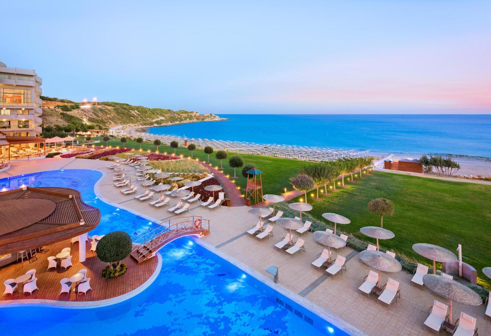 Elysium Resort & Spa skats no augšas uz baseinu kompleksu, dārzu un pludmali Rodas salā saulrieta laikā