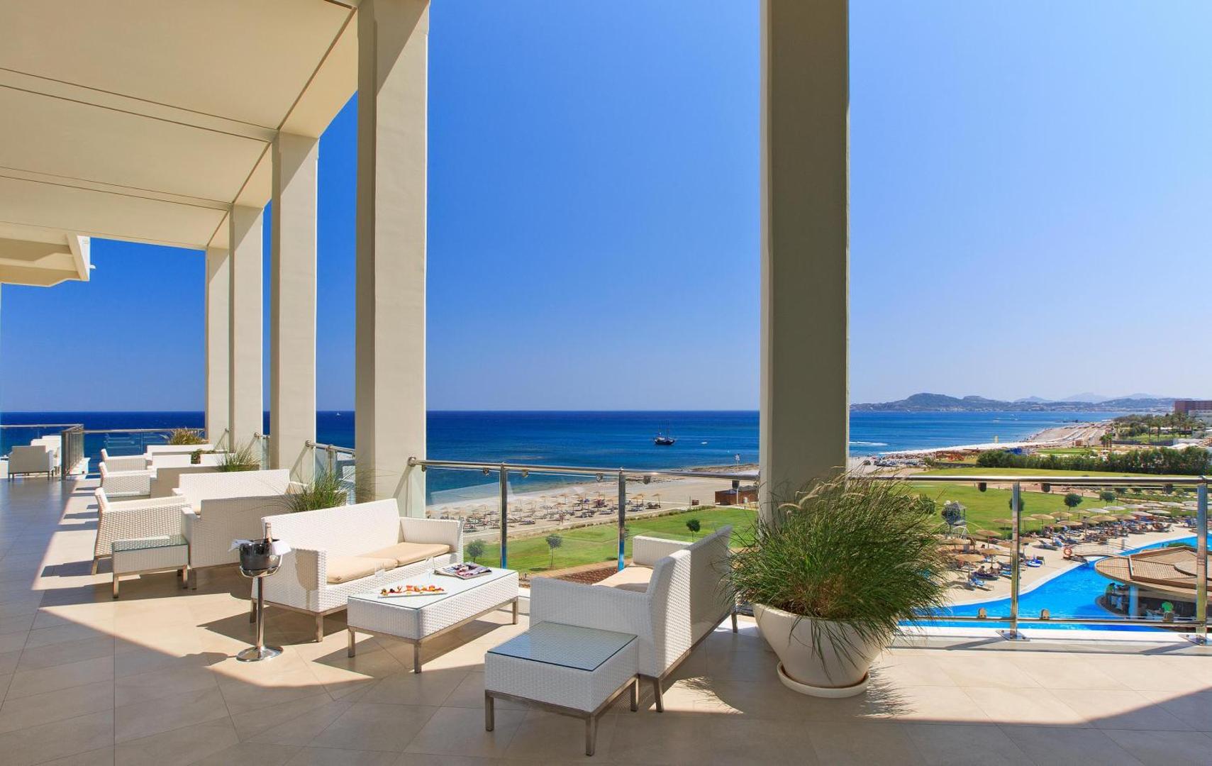 Elysium Resort & Spa plašā āra terase ar baltām mēbelēm un skatu uz baseinu un jūru Rodas salā