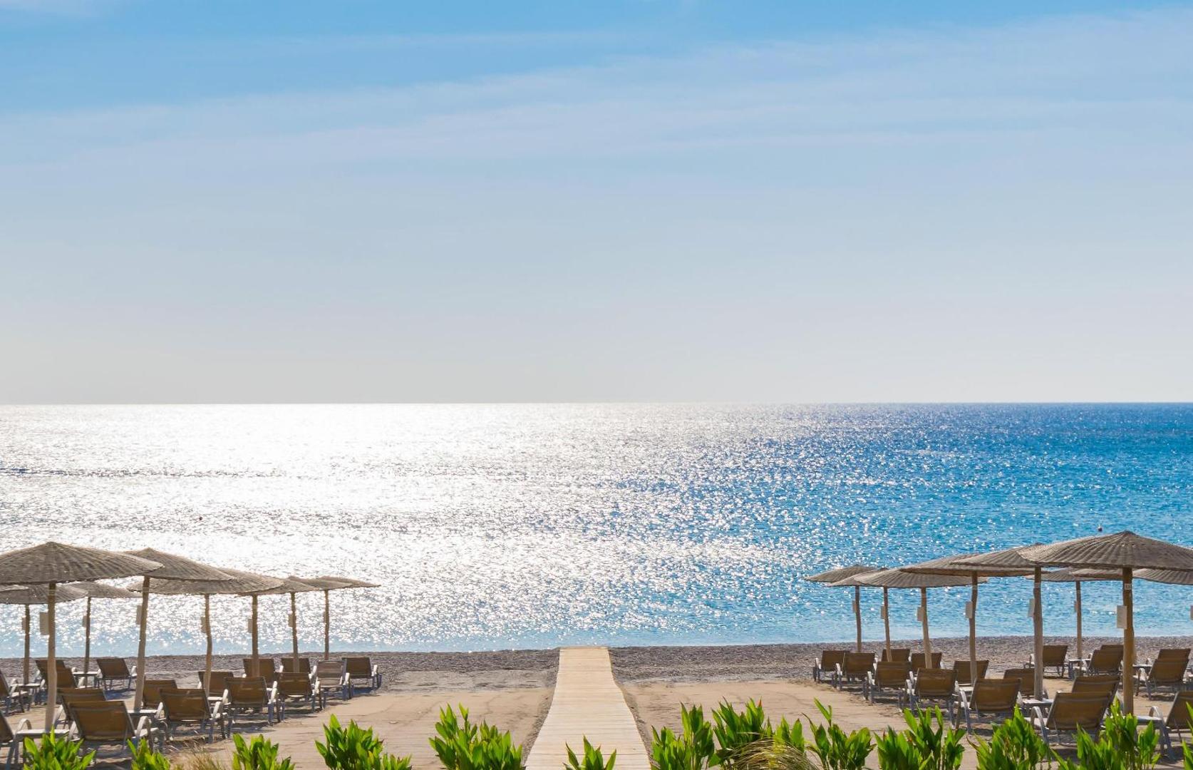 Elysium Resort & Spa privātā pludmale ar saulessargiem un zviļņiem pie dzidra ūdens Rodas salas piekrastē Grieķijā