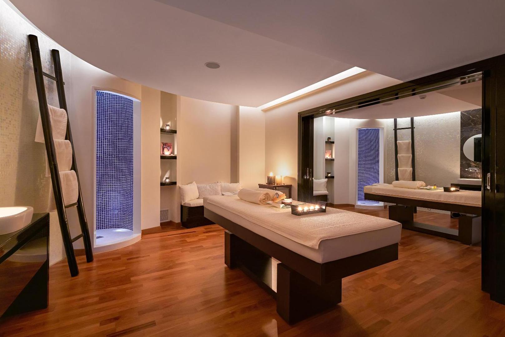 Elysium Resort & Spa plaša spa procedūru telpa ar divām masāžas gultām, koka grīdu un relaksējošu apgaismojumu Rodā