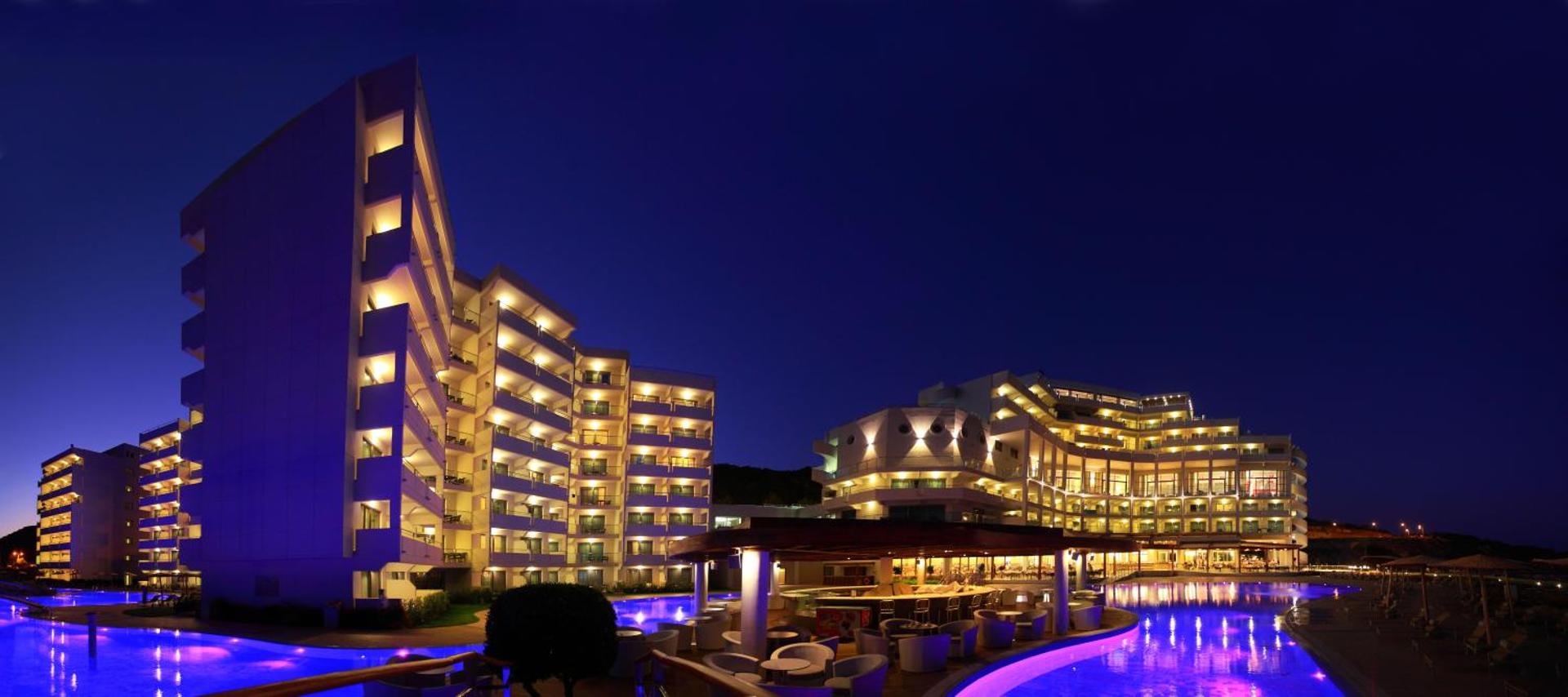 Elysium Resort & Spa nakts skats uz numuru korpusiem un izgaismoto baseinu zonu — moderna pieczvaigžņu viesnīca Rodas salā