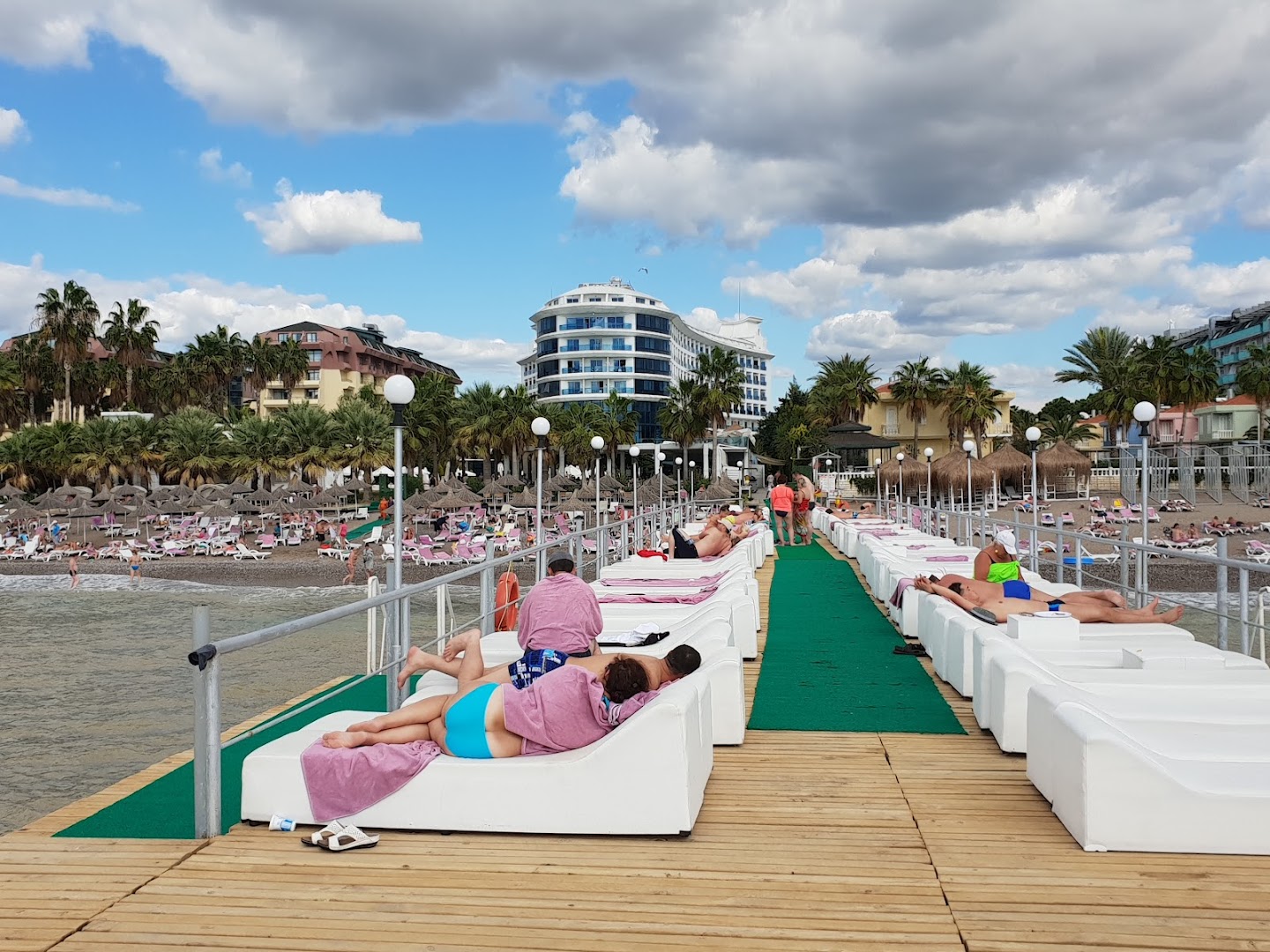 Q Premium Resort Hotel skats no mola uz viesnīcas galveno ēku, pludmali un atpūtniekiem uz mīkstajiem zviļņiem