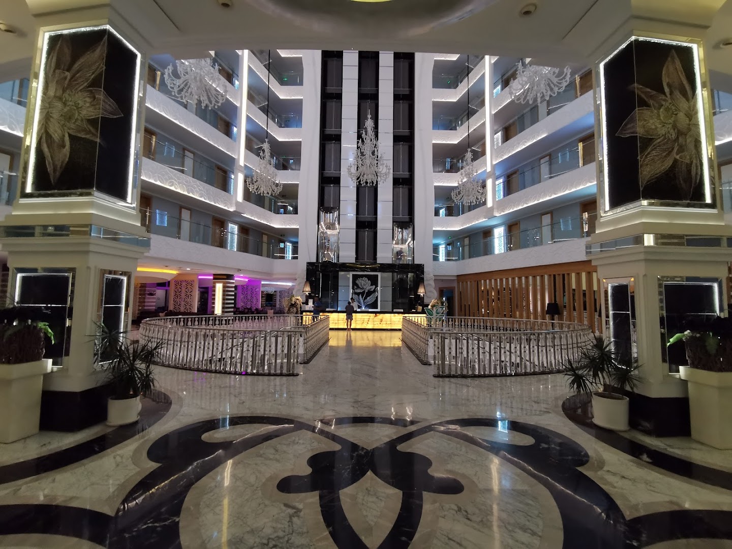 Q Premium Resort Hotel centrālā recepcijas zona un vestibila interjers vakarā ar dekoratīvām kolonnām un spoguļiem Alānijas piekrastē