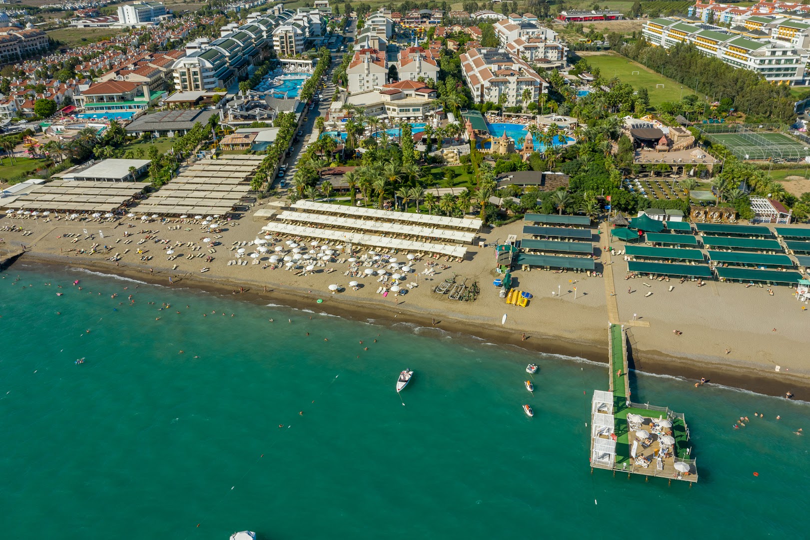 Aydinbey Famous Resort viesnīcas teritorija no putna lidojuma Belekā — skats uz baseiniem, pludmali un Vidusjūras piekrasti