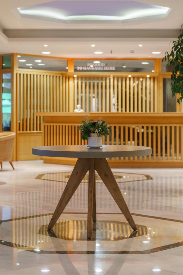 Viesnīcas Pearl Beach recepcijas zona ar koka apdari un marmora grīdu Retimno — centrālais galds ar ziediem un viesmīlīgu interjeru