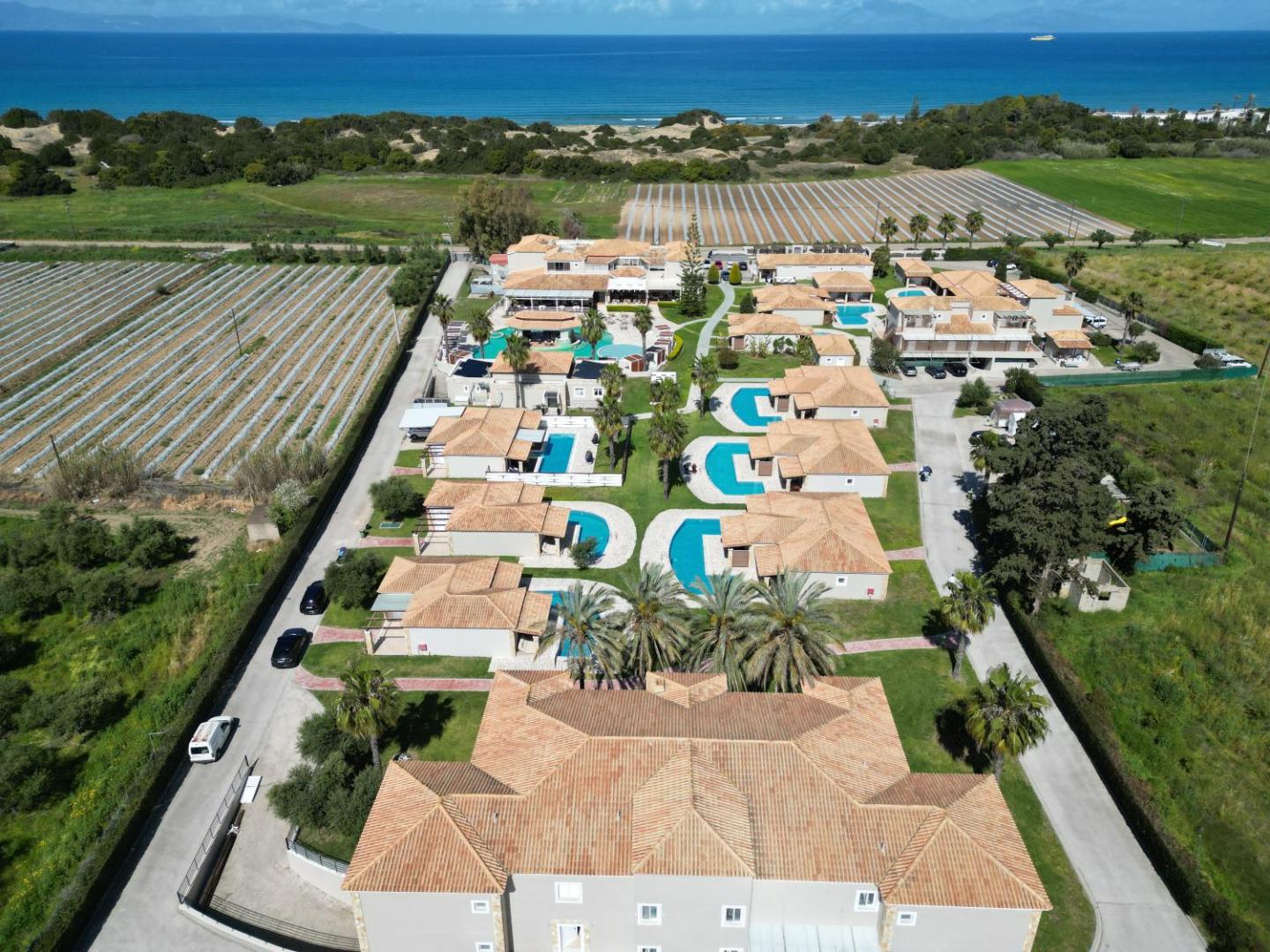 Olympia Golden Beach Resort & Spa aerofoto skats no putna lidojuma Peloponēsas piekrastē — viesnīcas komplekss ar bungalo, baseiniem un jūru fonā