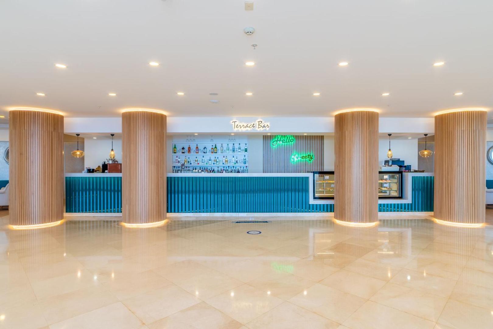 Kefaluka Resort modernais Terrace Bar vestibils ar gaišu marmora grīdu, stilīgām koka kolonnām un zilu bāra leti