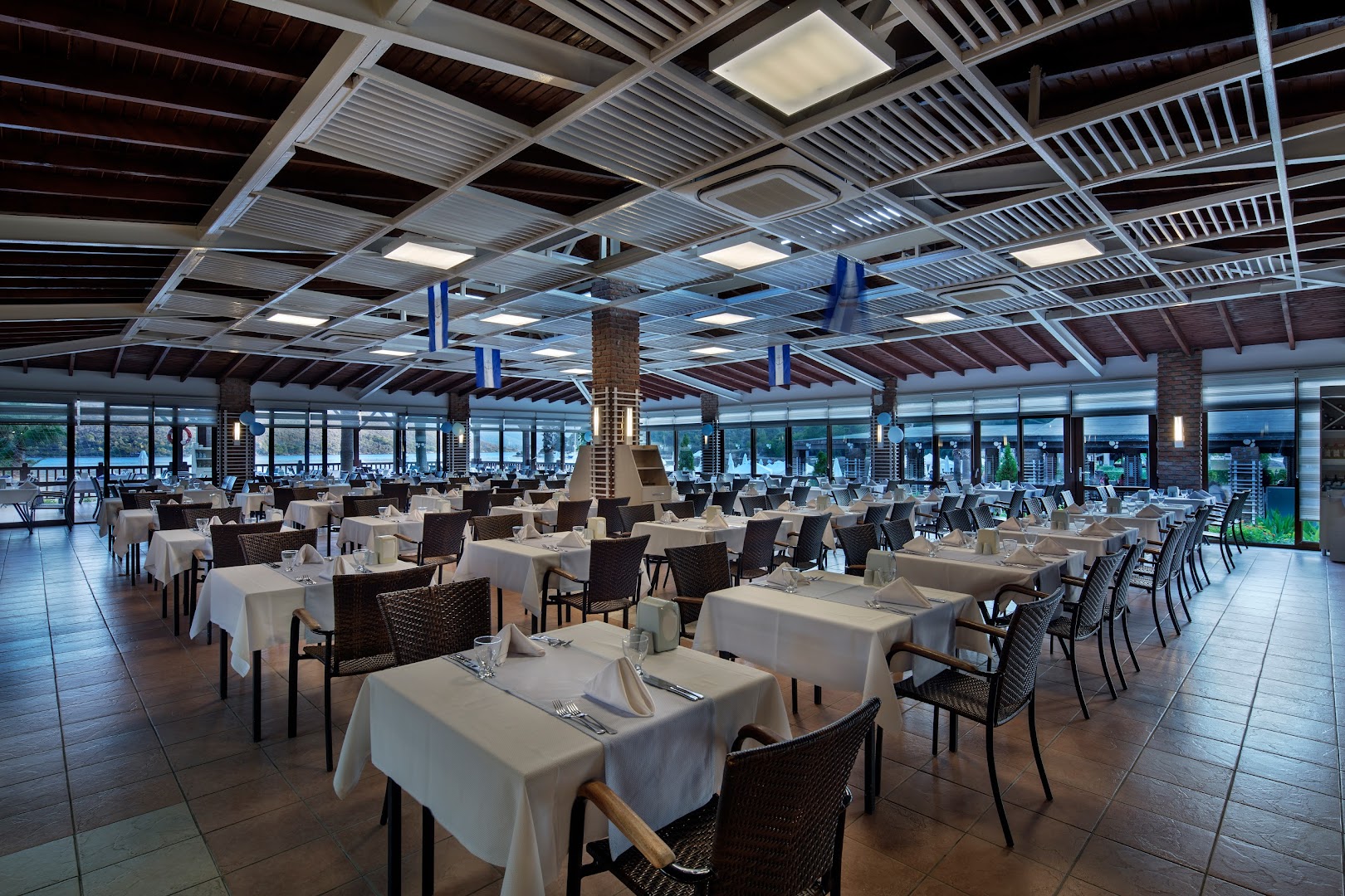 Crystal Green Bay Resort & Spa galvenais restorāns ar klātiem galdiem un skatu uz jūru Bodrumas piekrastē Turcijā