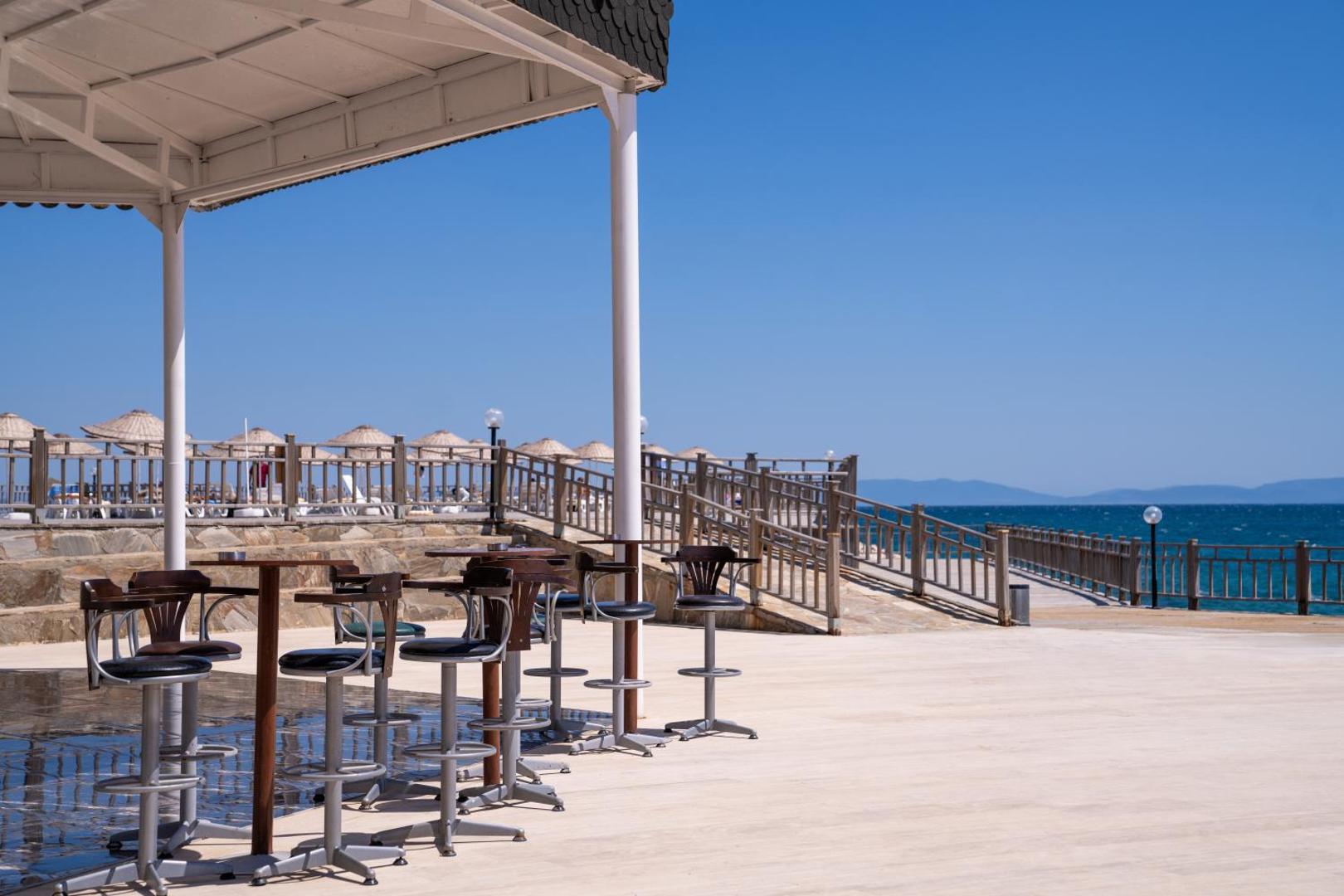 Anadolu Hotels Didim Club āra terase ar bāra krēsliem un galdiņiem pie jūras krasta zem nojumes