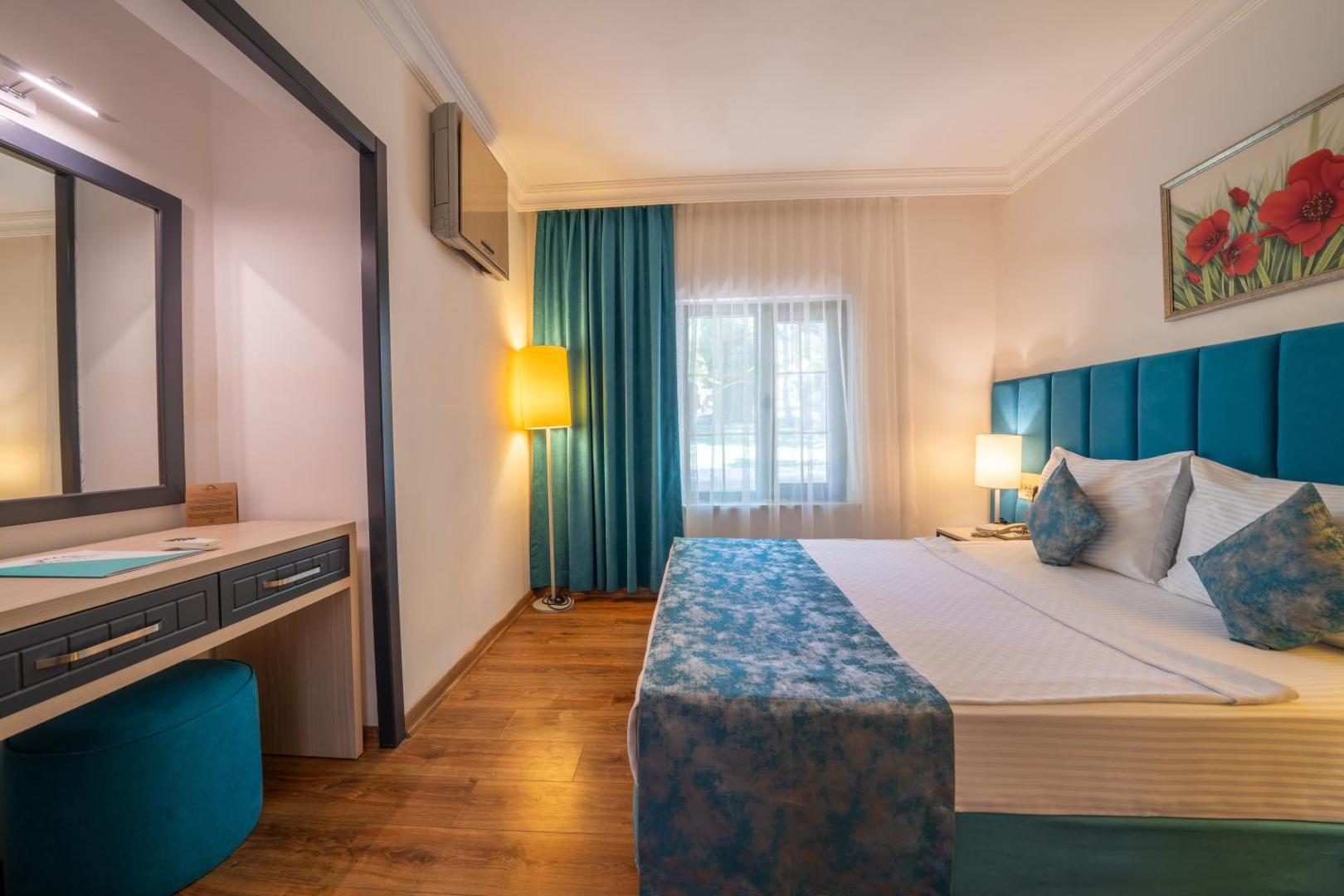 Anadolu Hotels Didim Club gaišs divvietīgs numurs ar ziliem akcentiem, tualetes galdiņu un lielu spoguli Didimā, Turcijā