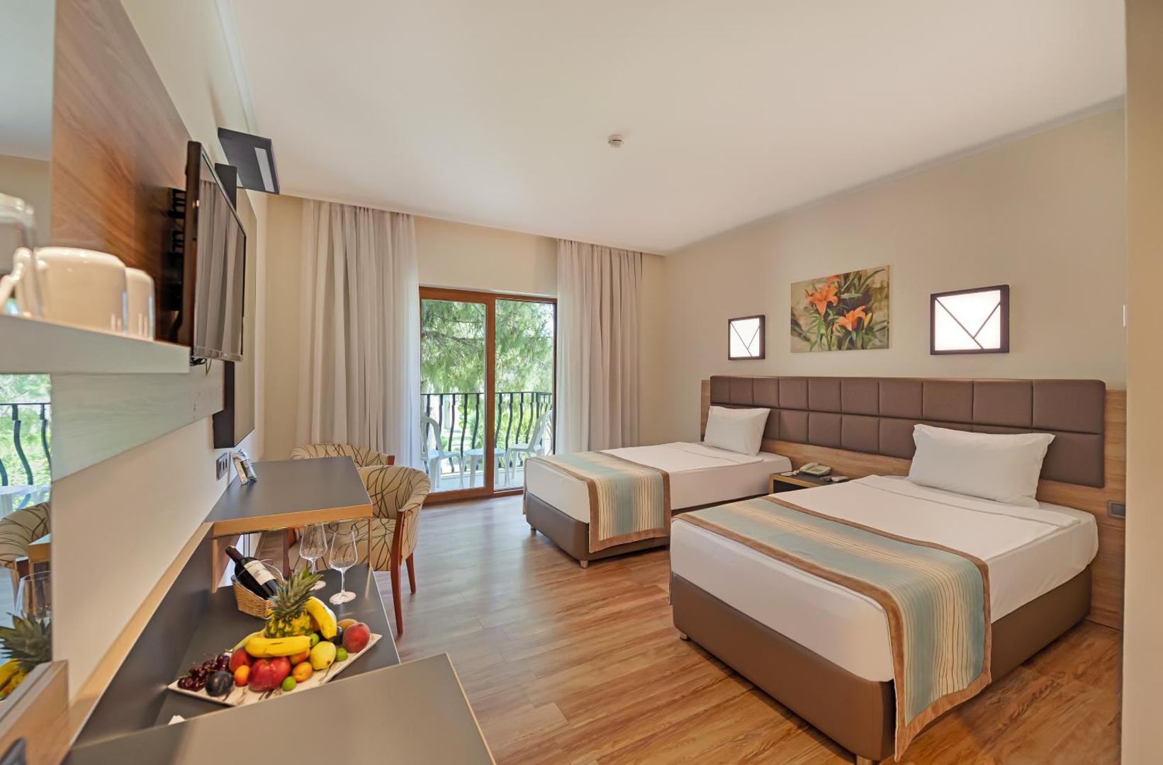 Kimeros Park Holiday Village gaišs divvietīgs numurs ar atsevišķām gultām, balkonu, koka grīdu un augļu plati uz galda Kemeras reģionā
