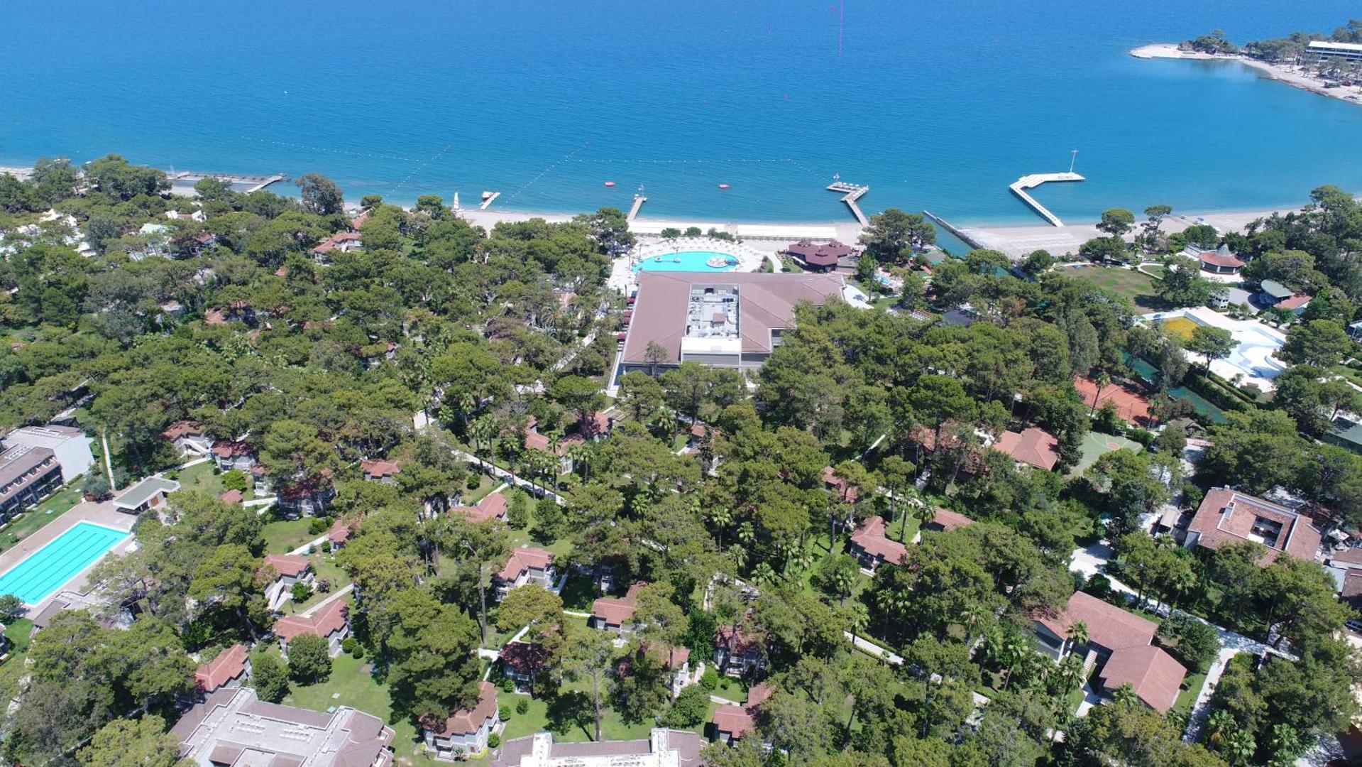Kimeros Park Holiday Village teritorijas skats no putna lidojuma, parādot bungalo tipa numurus priežu meža ielokā pie jūras.