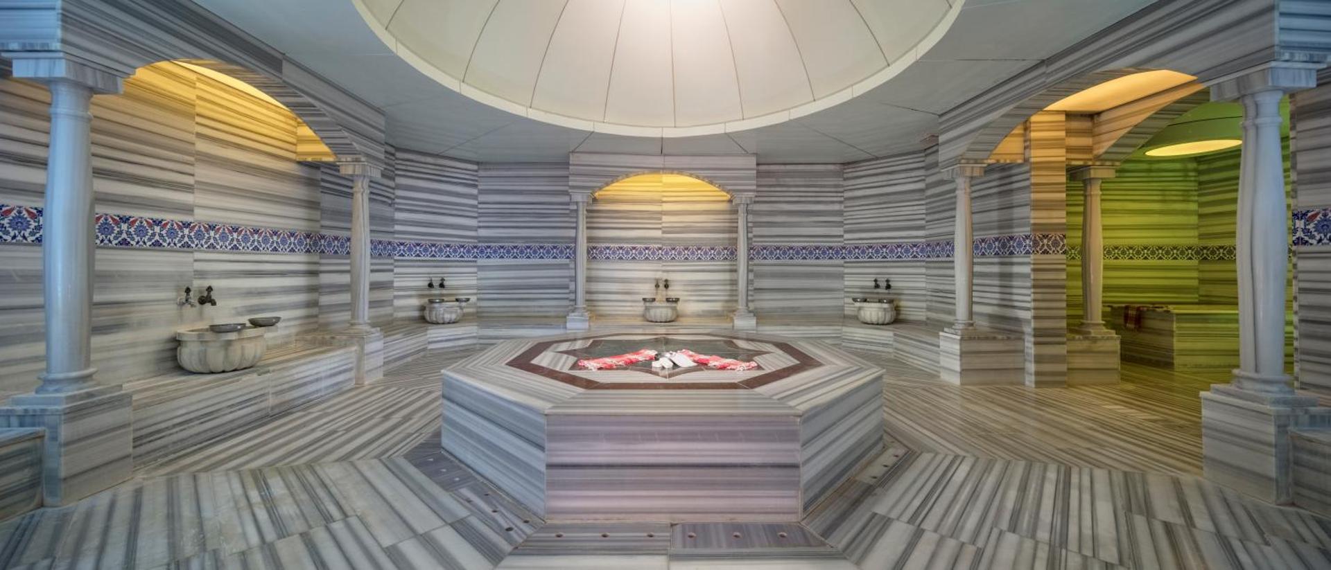 Tradicionāls turku hamams Aydinbey Kings Palace viesnīcā ar marmora apdari, centrālo akmeni un dekoratīvām flīzēm spa zonā