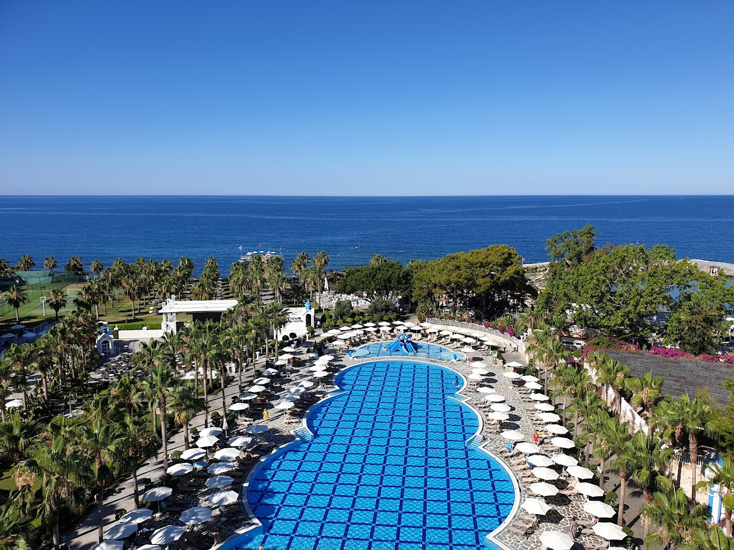 Rubi Platinum SPA Resort & Suites lielais āra baseins ar saulessargiem un zviļņiem, ko ieskauj palmas un skats uz jūru