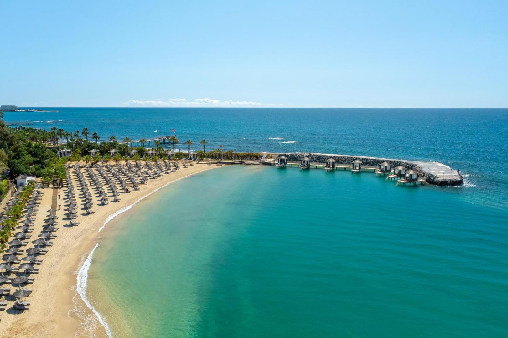 Rubi Platinum SPA Resort & Suites privātā smilšu pludmale un līcis ar saulessargiem un bungalo Alānijā, Turcijā — skats no augšas