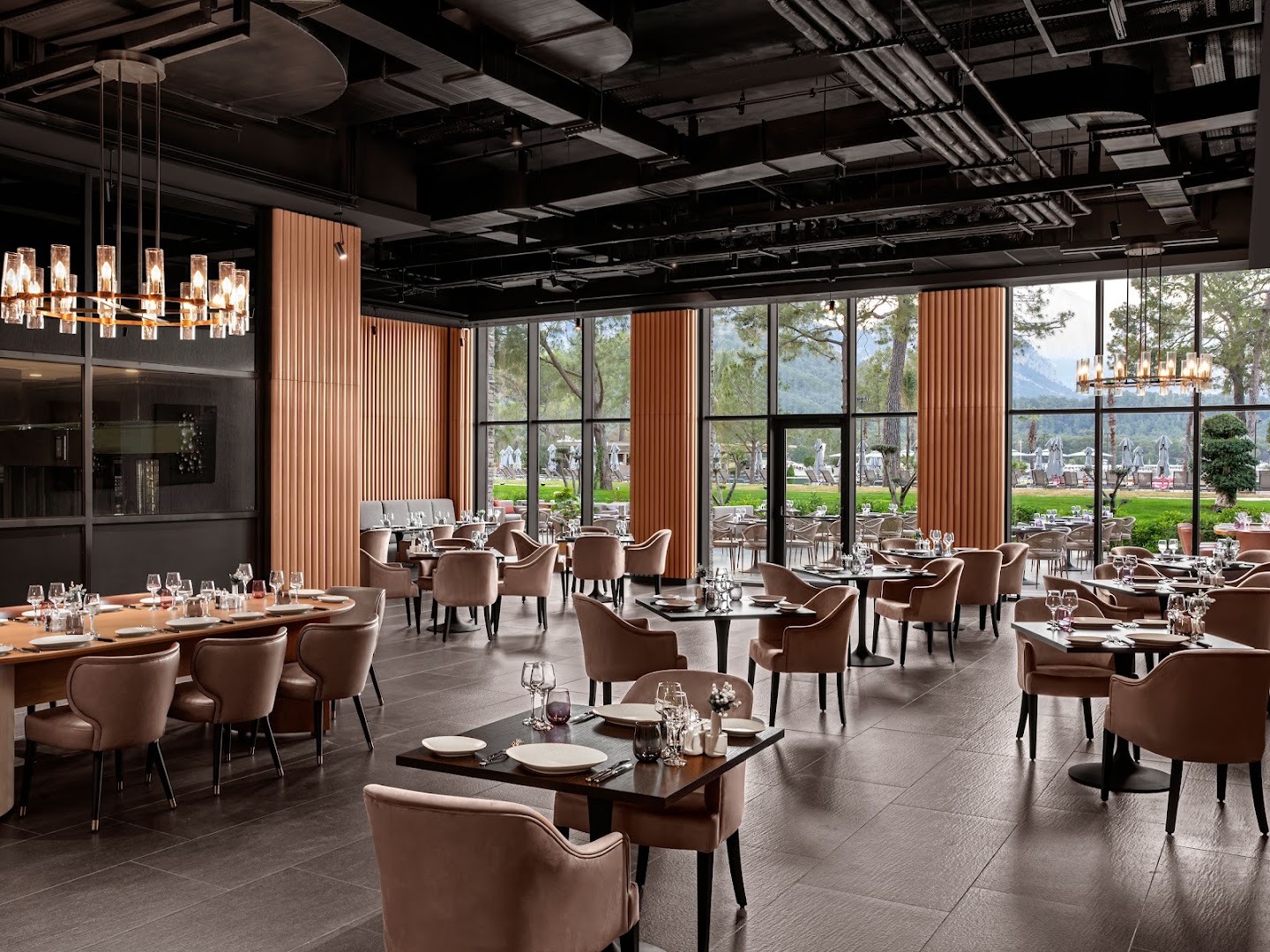 NG Phaselis Bay a la carte restorāns ar tumšu, modernu interjeru un lieliem logiem uz Kemeras kalniem un priežu mežu