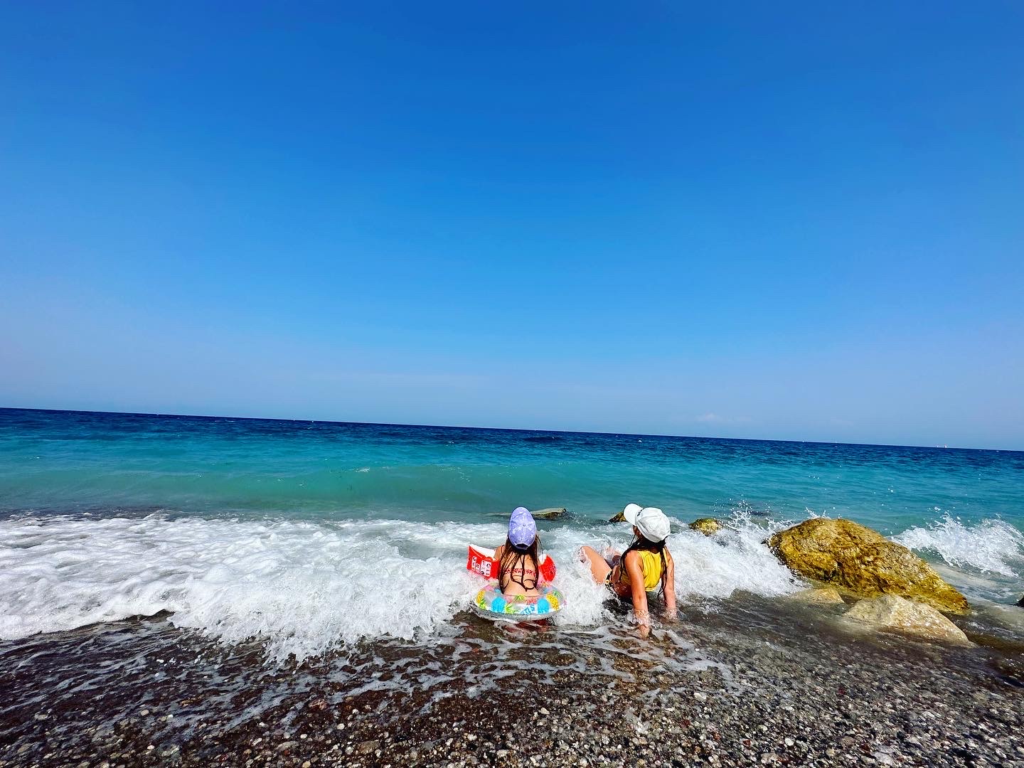 Bērni rotaļājas Belair Beach viesnīcas pludmales krastā Rodas salā, baudot dzidro Egejas jūras ūdeni un viļņus