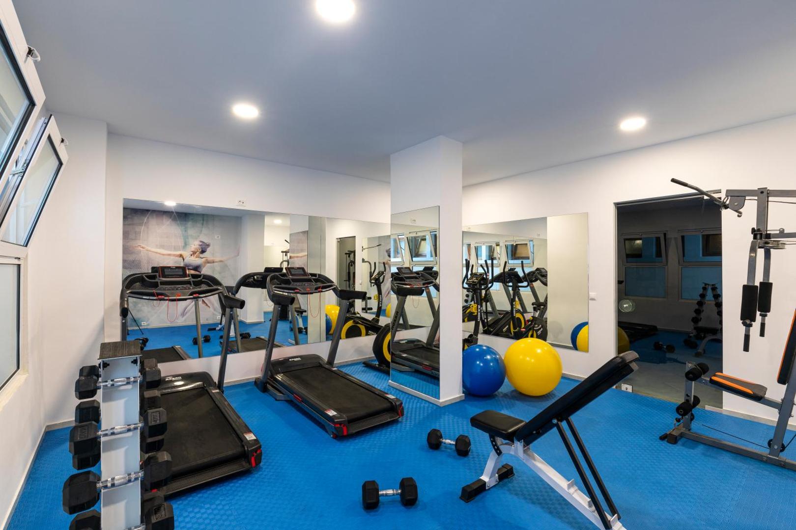 Belair Beach fitness centrs ar skrejceliņiem, hantelēm un vingrošanas bumbām — gaiša sporta zāle aktīvam ceļojumam Rodas salā.