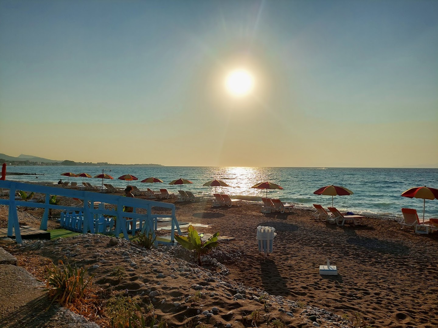 Saulriets Belair Beach privātajā pludmalē Rodas salā, Grieķijā — saulessargi un sauļošanās krēsli jūras krastā vakara gaismā