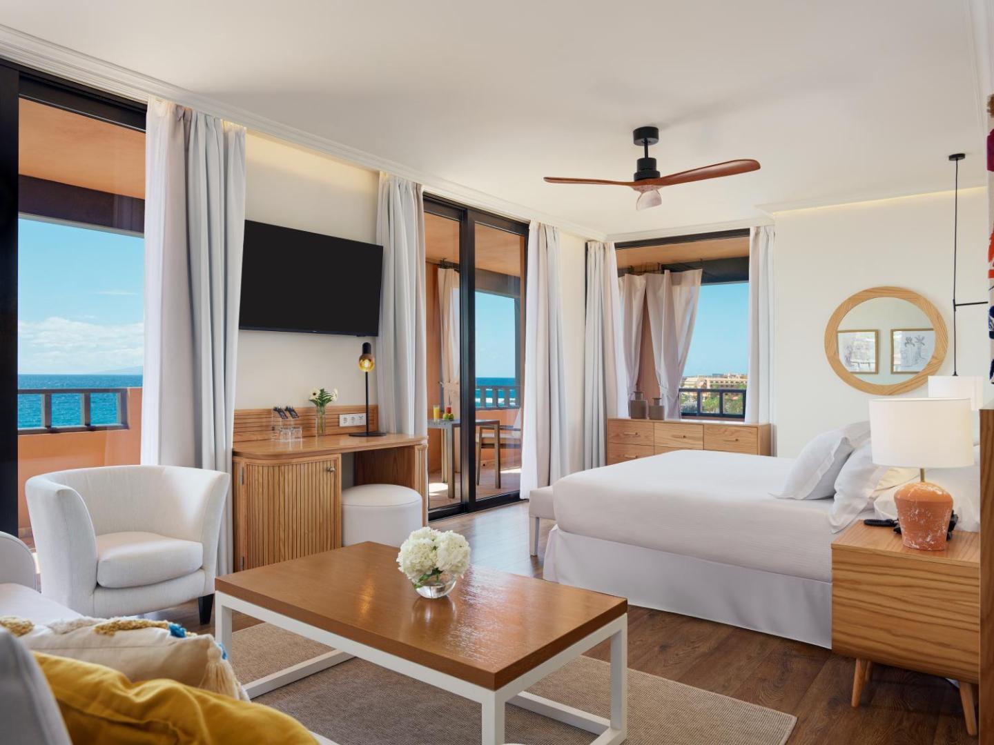 H10 Costa Adeje Palace numura interjers ar skatu uz okeānu, koka mēbelēm, televizoru un plašu terasi