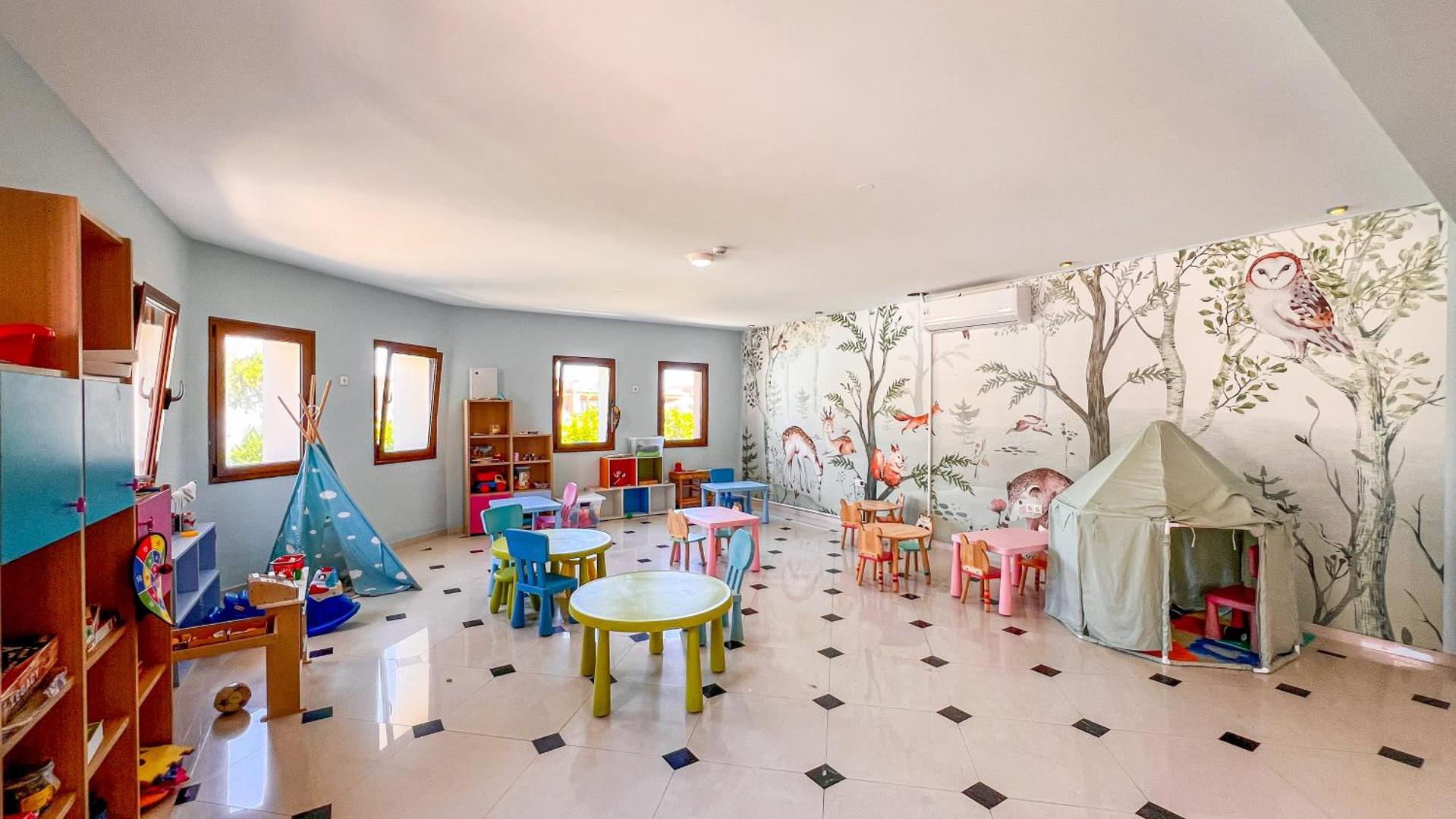 Atrium Palace Thalasso Spa Resort And Villas bērnu klubs ar krāsainiem galdiem, teltīm un meža dzīvnieku sienas gleznojumiem Rodas salā