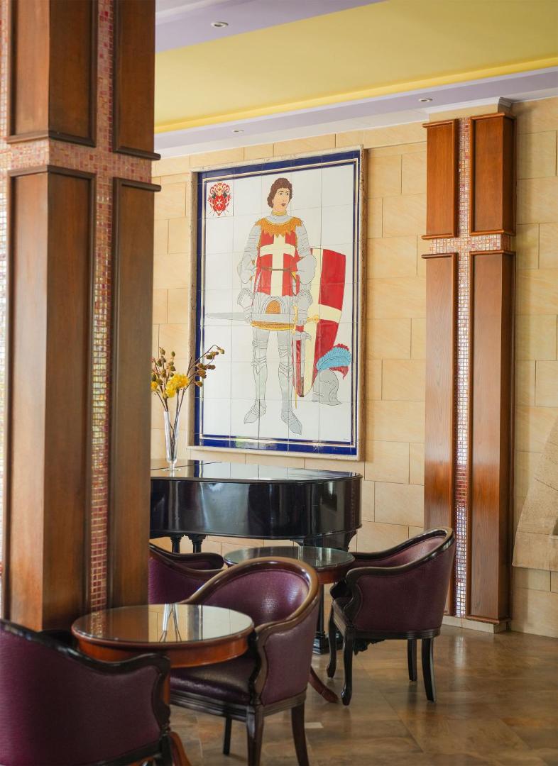 Atrium Palace viesnīcas interjera detaļa ar flīžu mozaīku, kurā attēlots bruņinieks, un melnu flīģeli atpūtas zonā