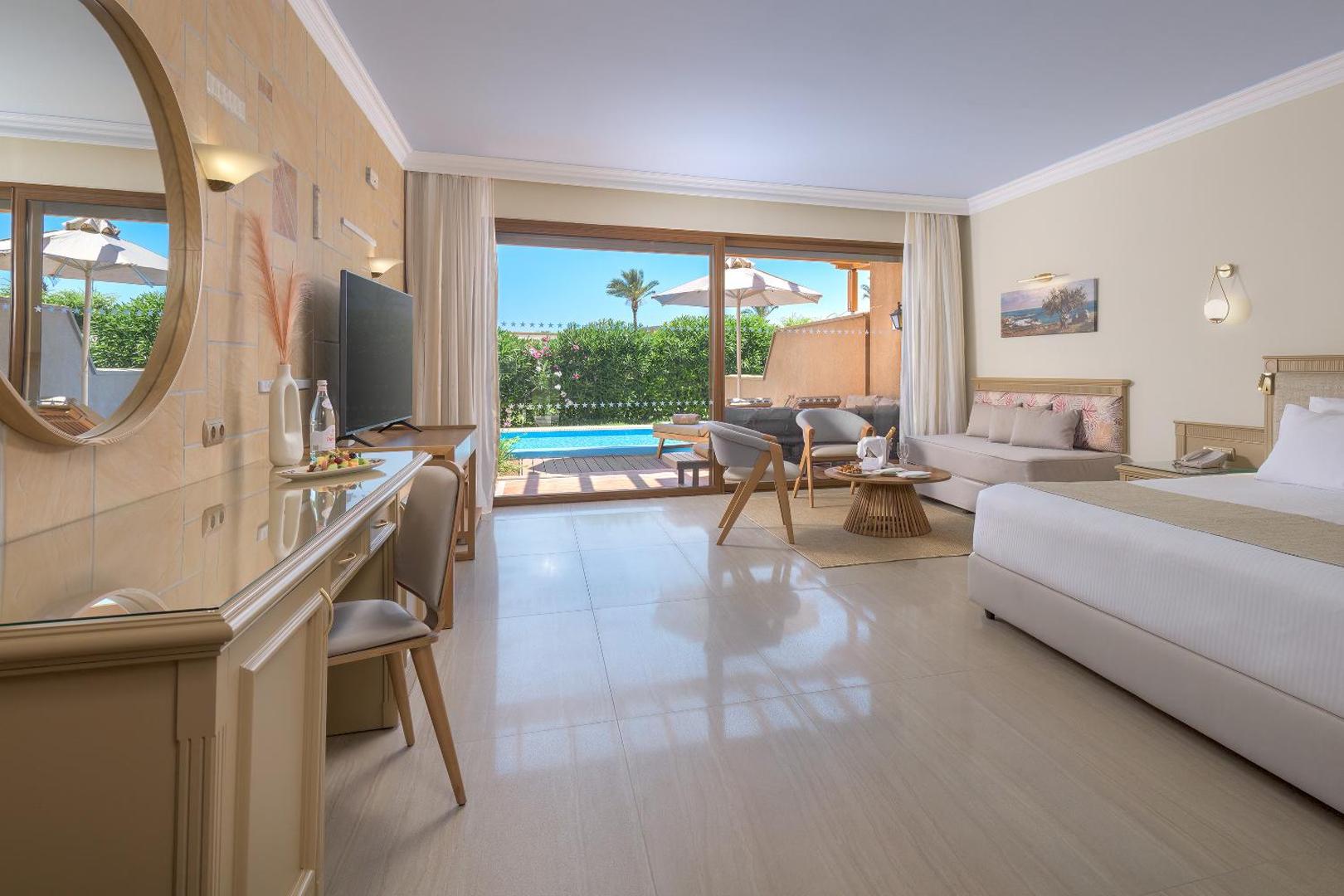Atrium Palace Thalasso Spa Resort numurs ar atpūtas zonu, dīvānu un izeju uz terasi pie baseina Rodas piekrastē.