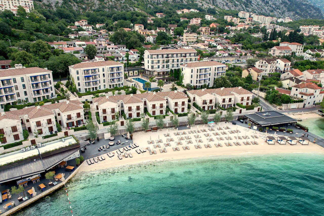 HUMA Kotor Bay Hotel & Villas pludmales zona ar saulessargiem, restorānu un skatu uz Kotoras līča ūdeņiem