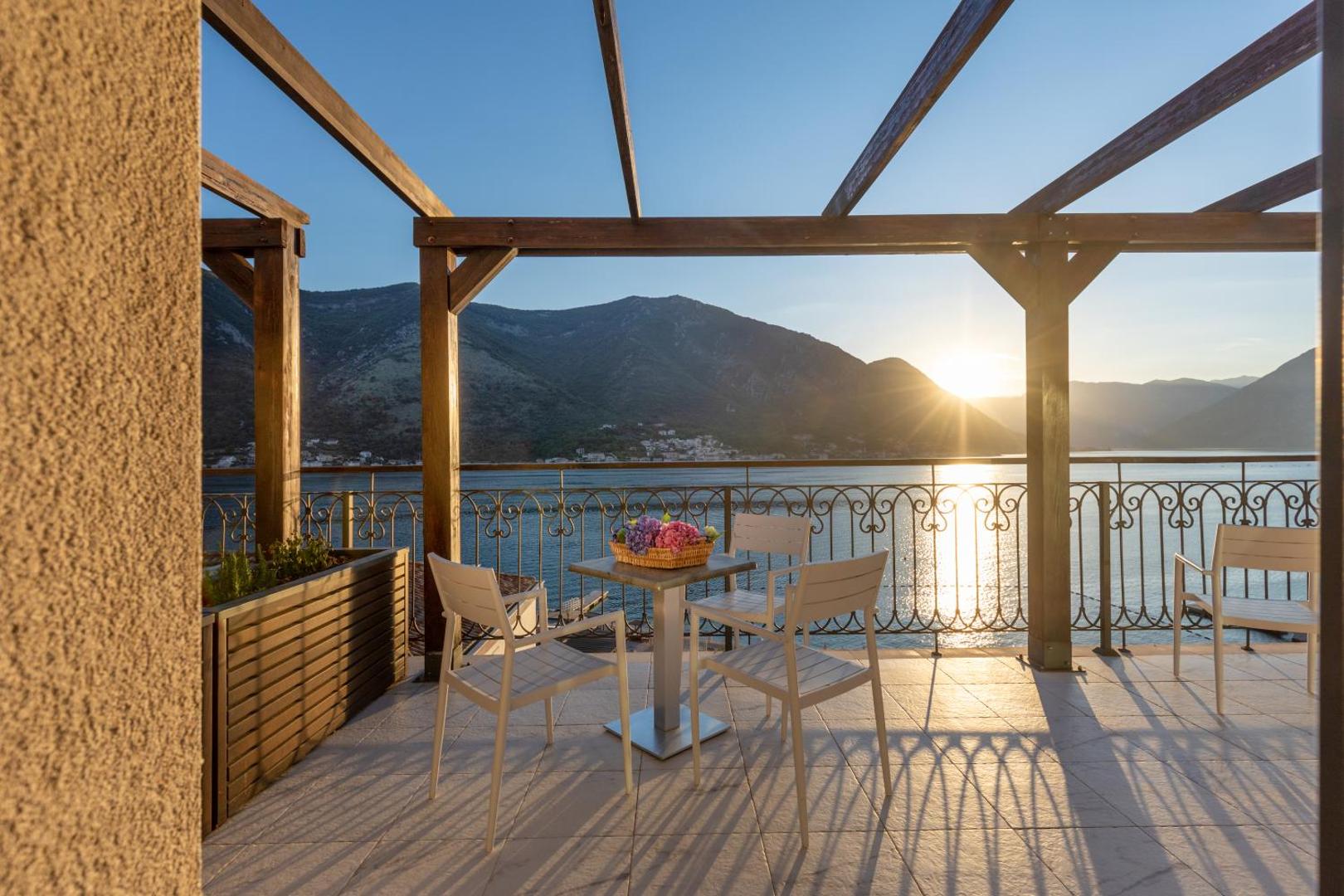 HUMA Kotor Bay Hotel & Villas āra terase ar koka pergolu saulrieta laikā, skats uz Kotoras līča kalniem un jūru