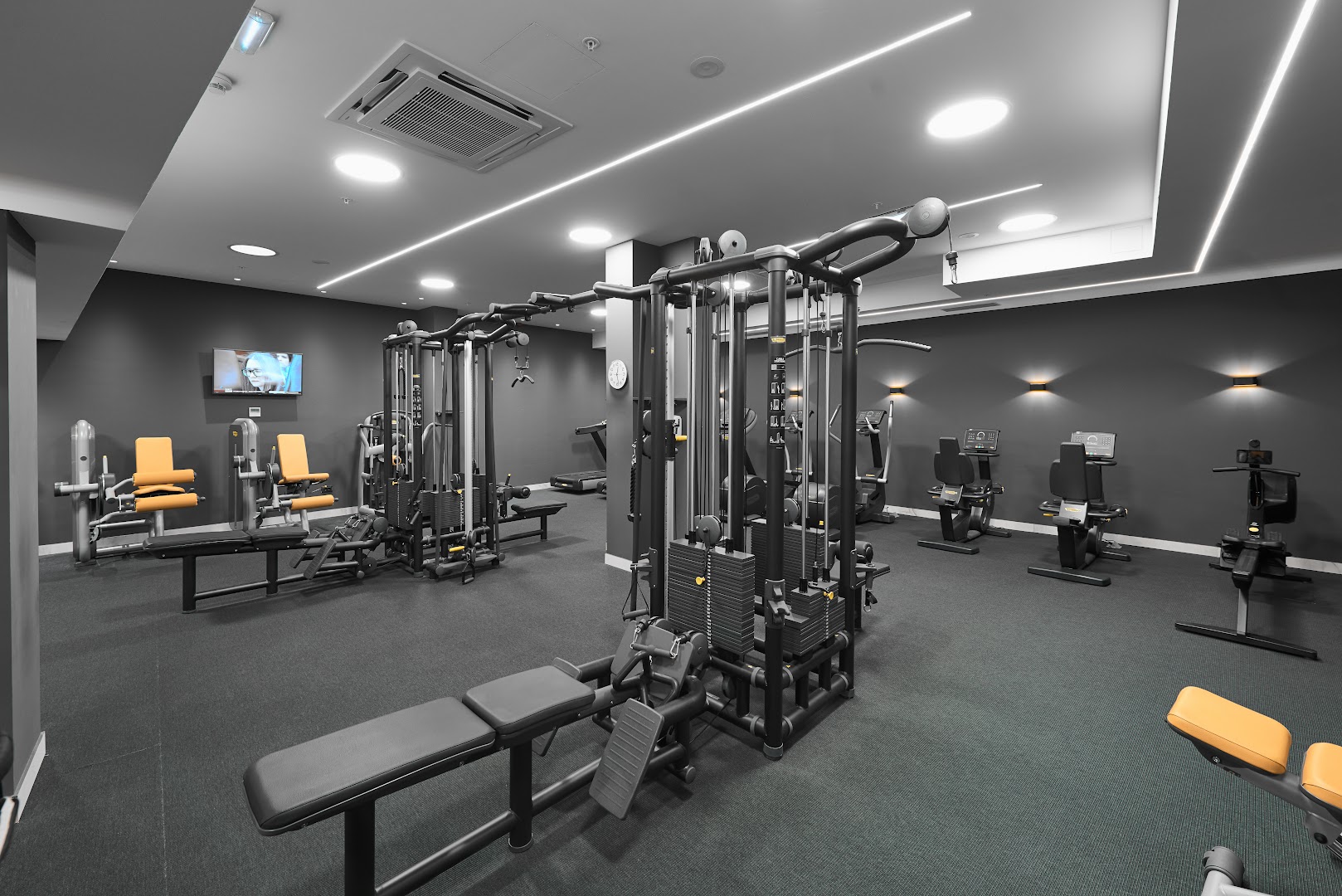 Moderns HUMA Kotor Bay Hotel & Villas fitness centrs ar Technogym trenažieriem, brīvajiem svariem un mūsdienīgu apgaismojumu